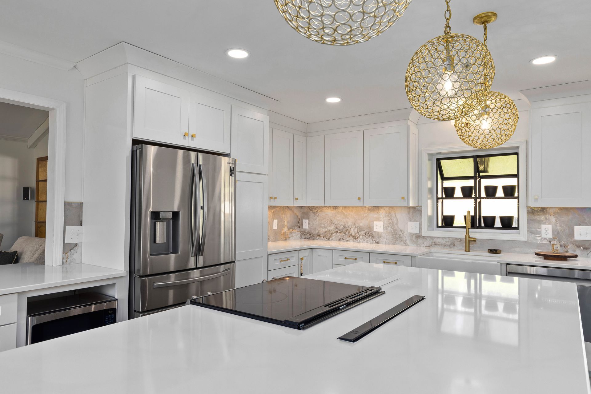 A kitchen with white cabinets , stainless steel appliances and a large island.