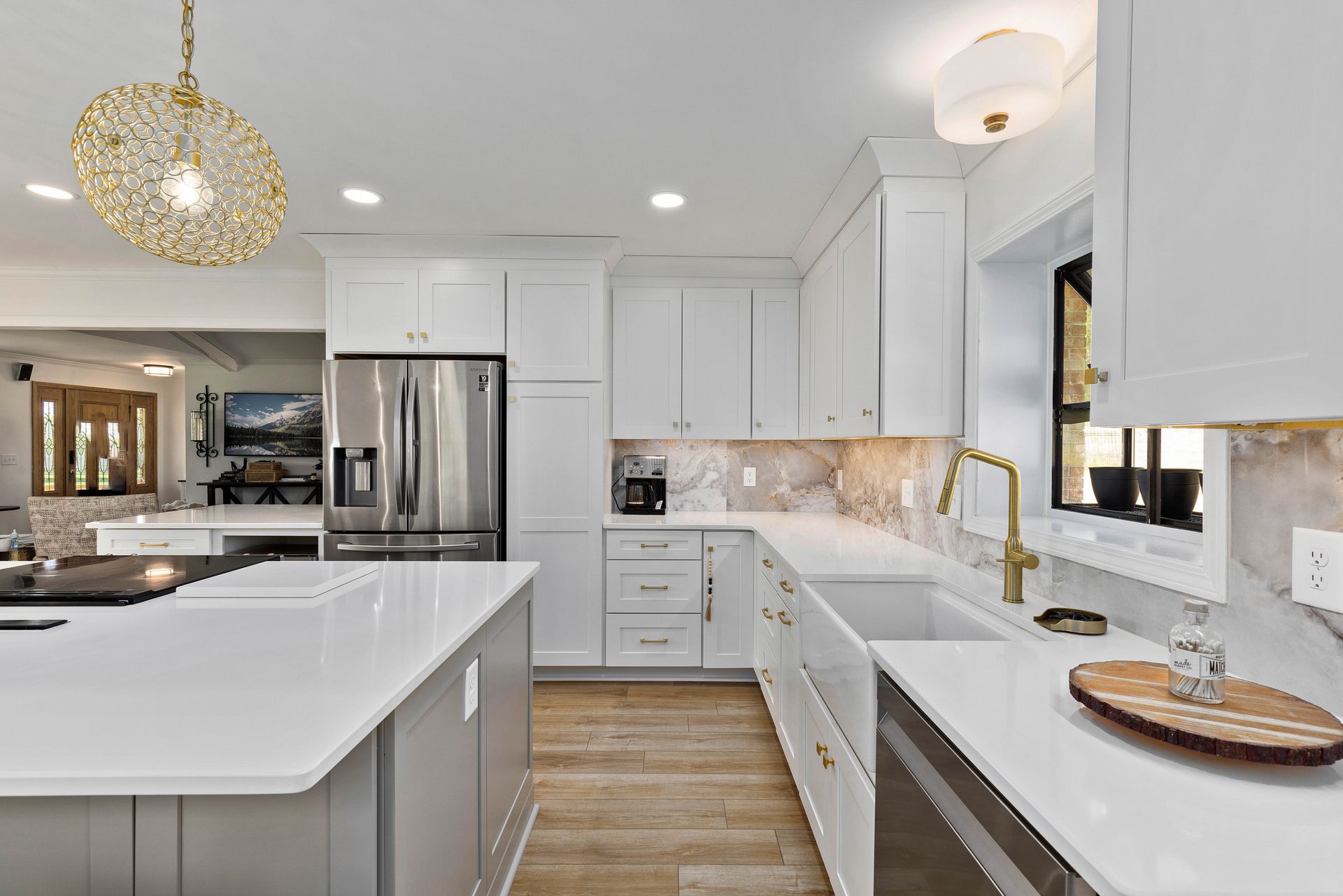 A kitchen with white cabinets , stainless steel appliances , a sink , and a refrigerator.