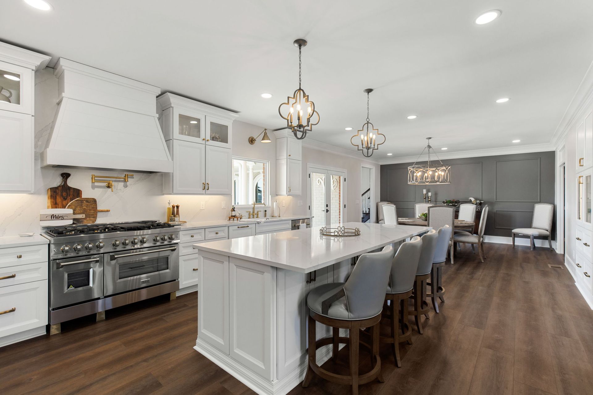 A kitchen with white cabinets , stainless steel appliances , and a large island.
