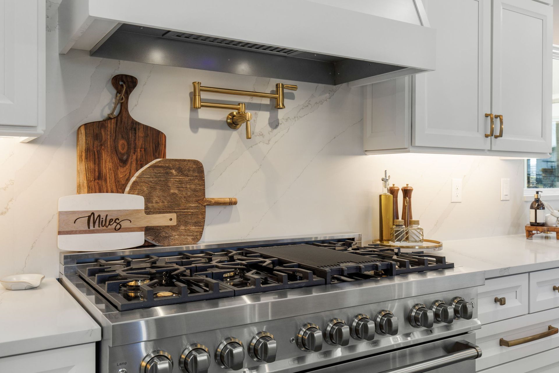 A kitchen with a stove top oven and a cutting board on the wall.
