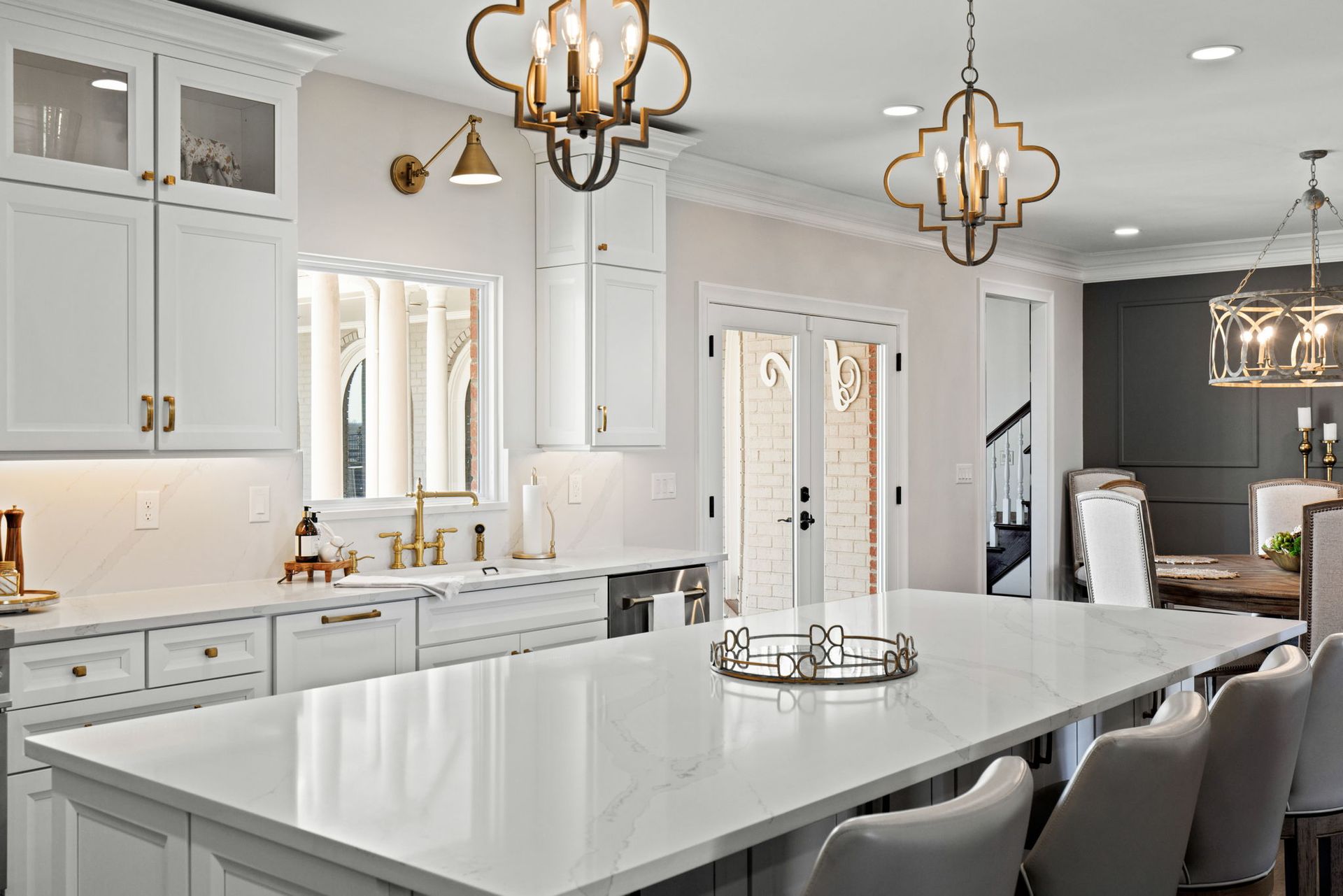 A kitchen with white cabinets , white counter tops , and a large island.