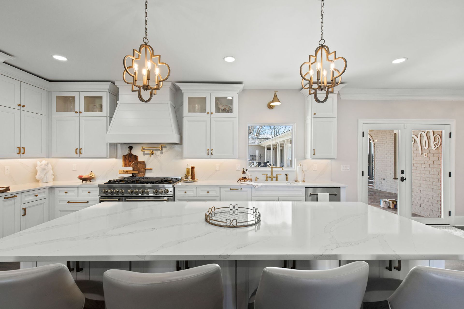 A kitchen with white cabinets , a large island , a stove and a sink.