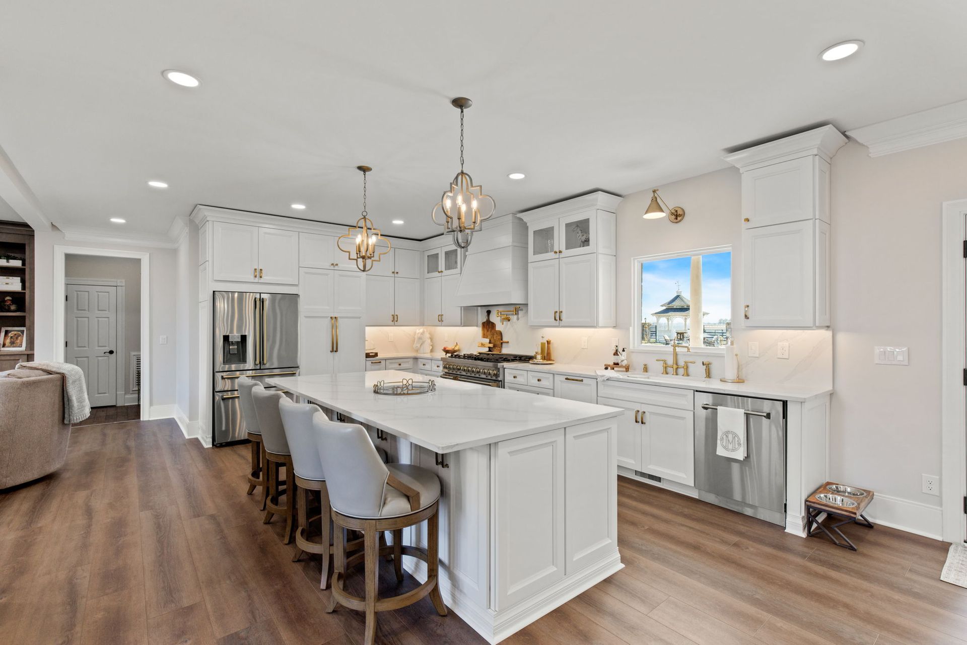 A kitchen with white cabinets , stainless steel appliances , hardwood floors and a large island.