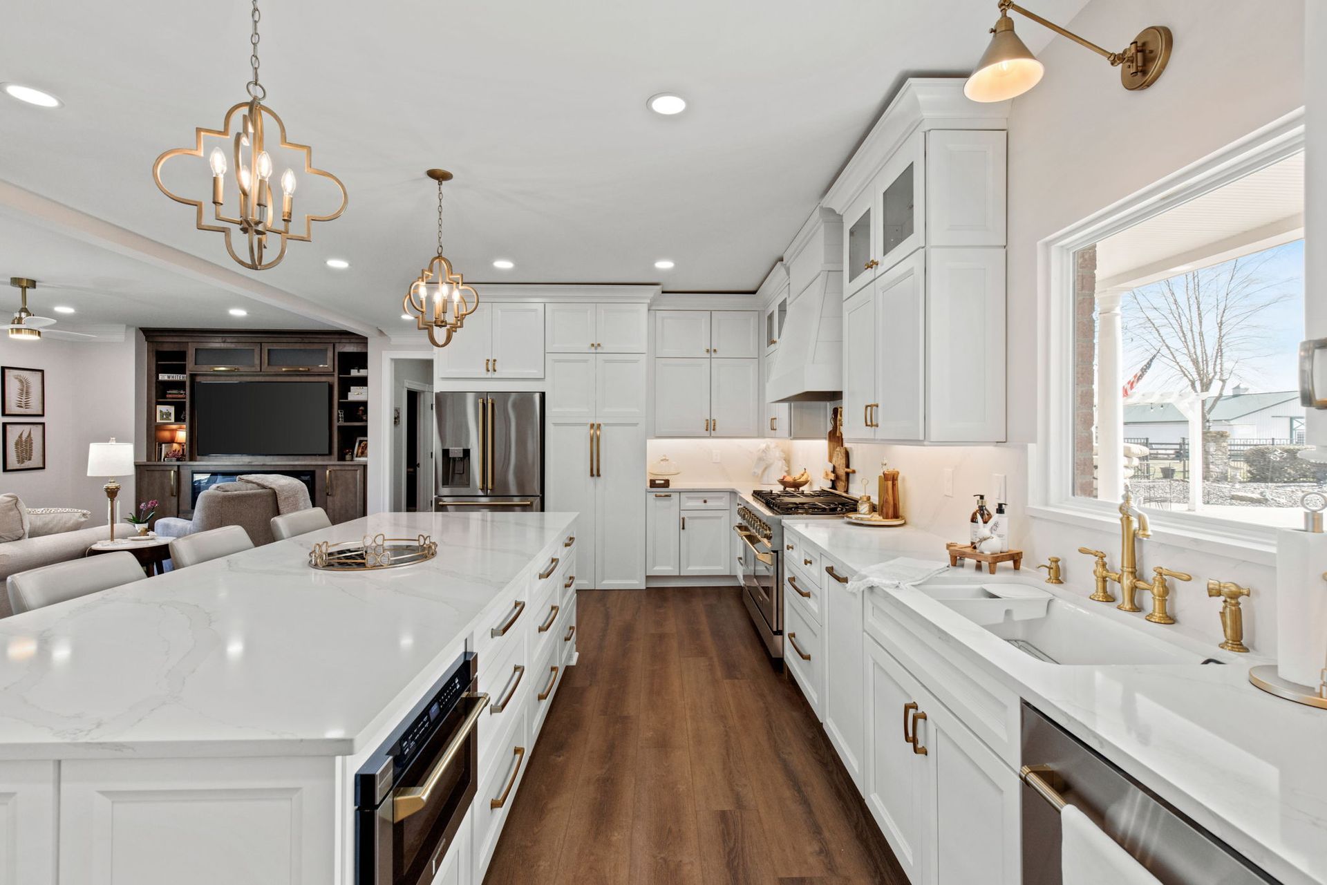A kitchen with white cabinets , stainless steel appliances , a sink , and a large island.