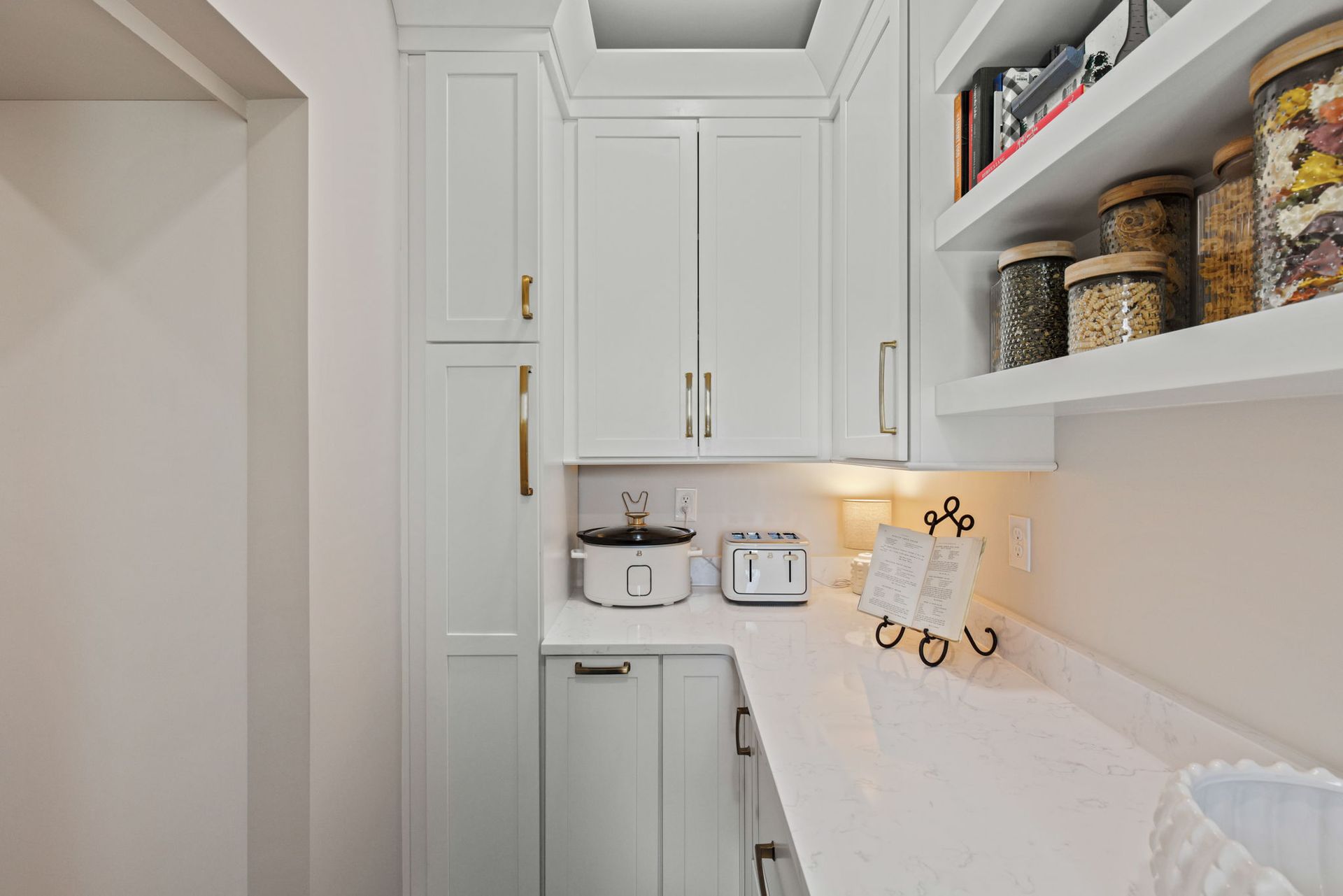 A kitchen with white cabinets , white counter tops , and white shelves.
