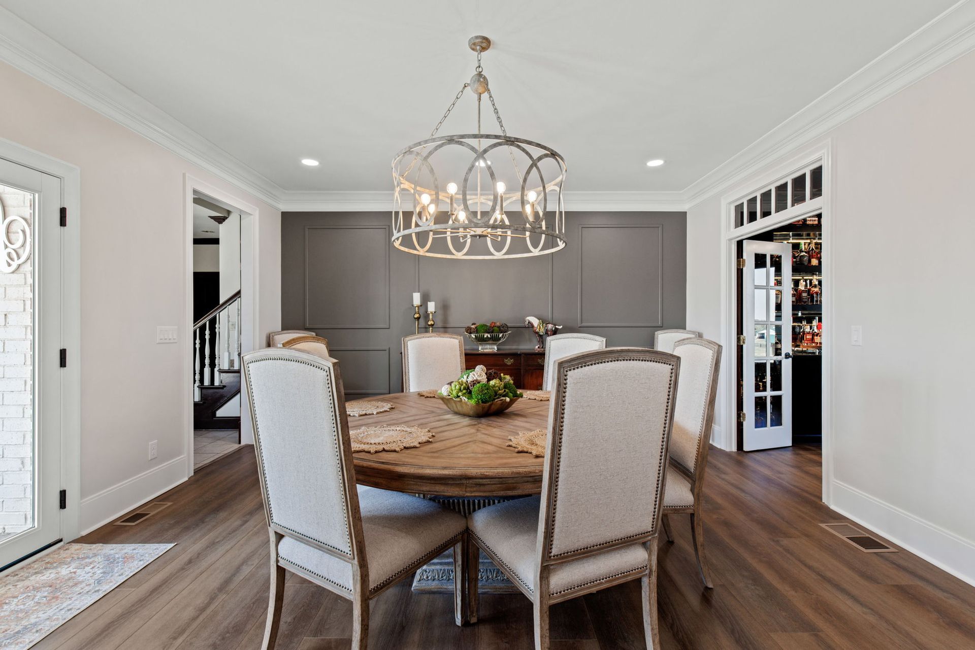 A dining room with a round table and chairs and a chandelier.