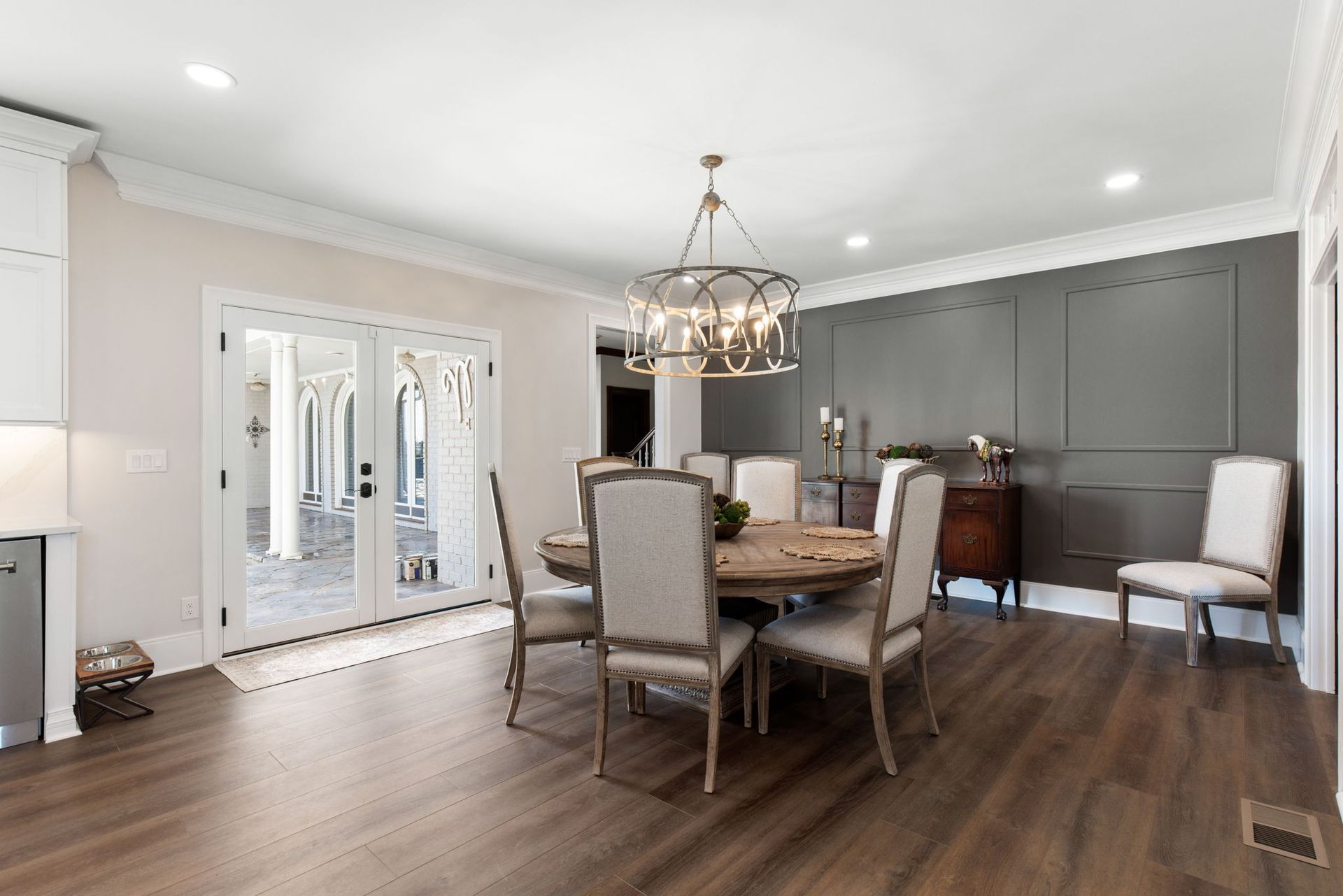 A dining room with a round table and chairs and a chandelier.