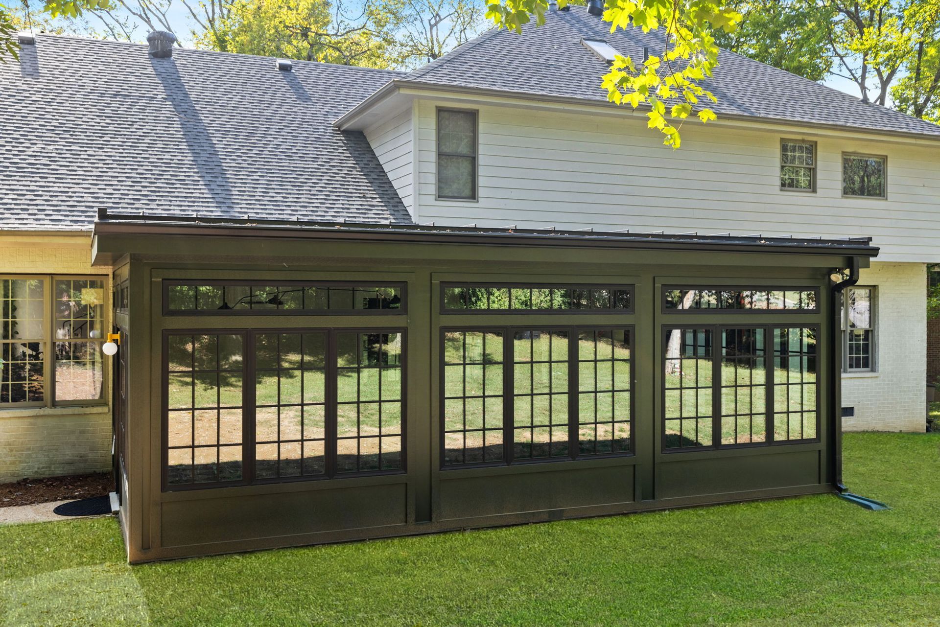A screened in porch is sitting in the backyard of a house.