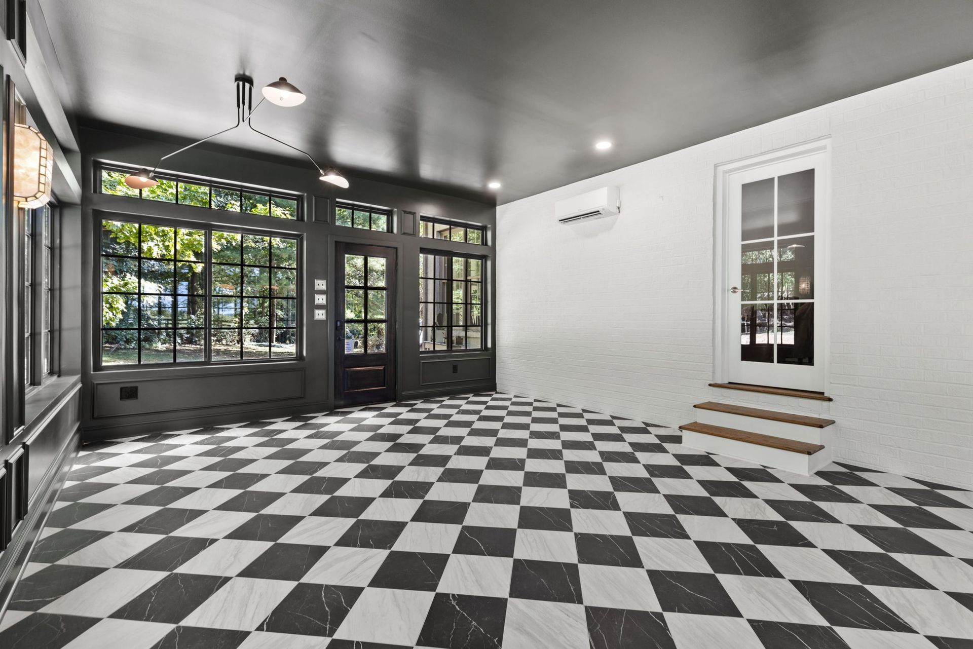 An empty room with a checkered floor and windows.