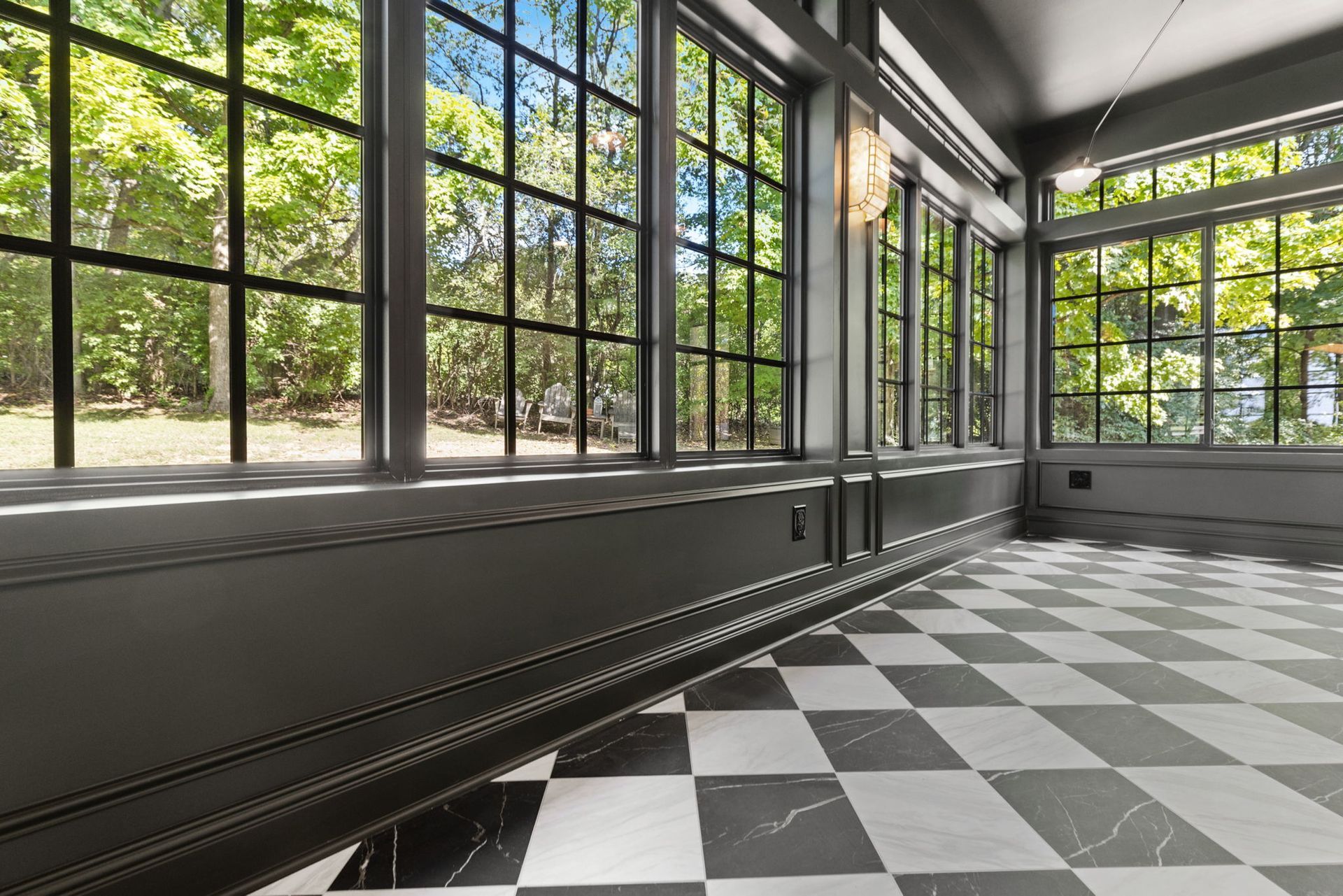 An empty room with a checkered floor and lots of windows.