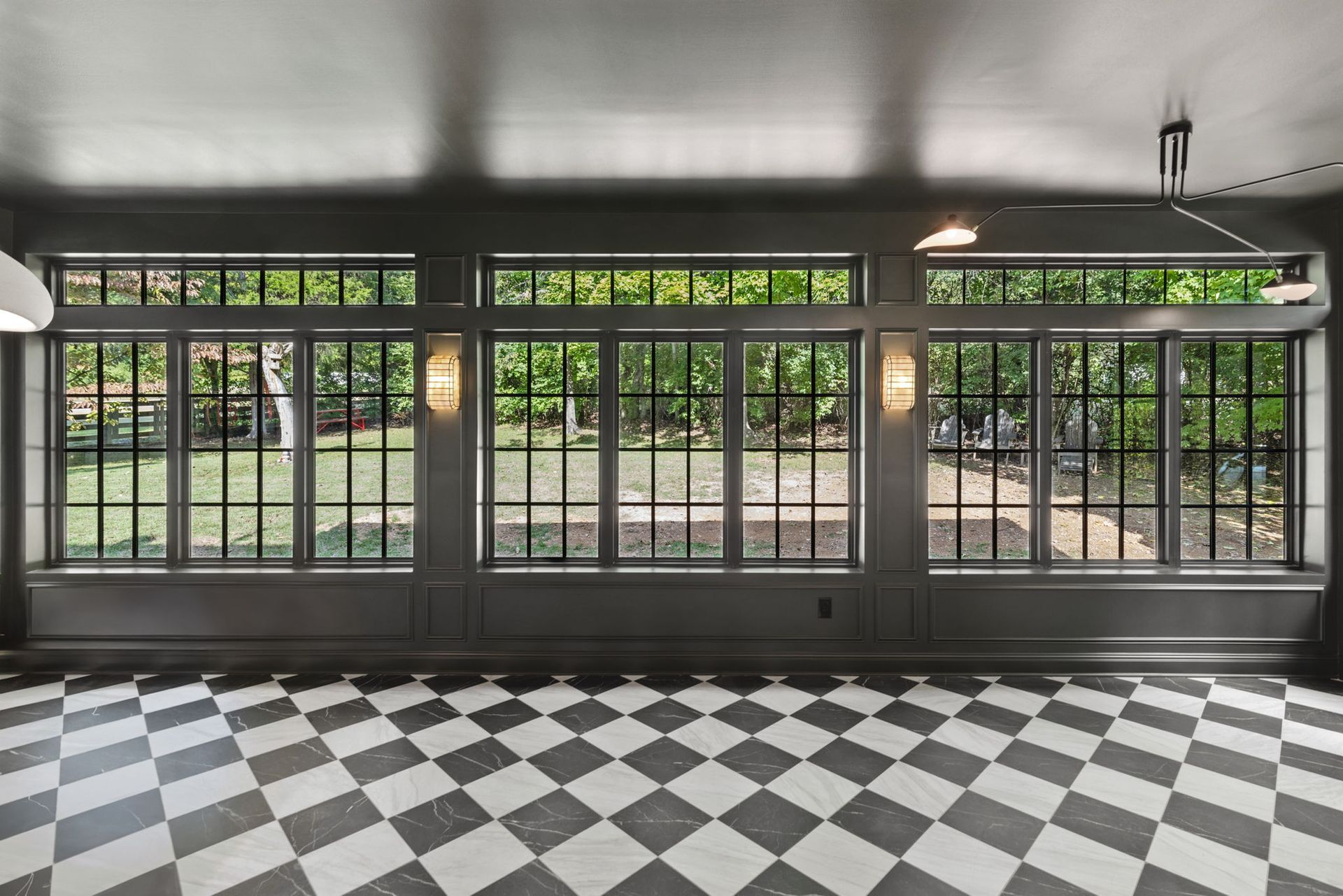 An empty room with a checkered floor and lots of windows