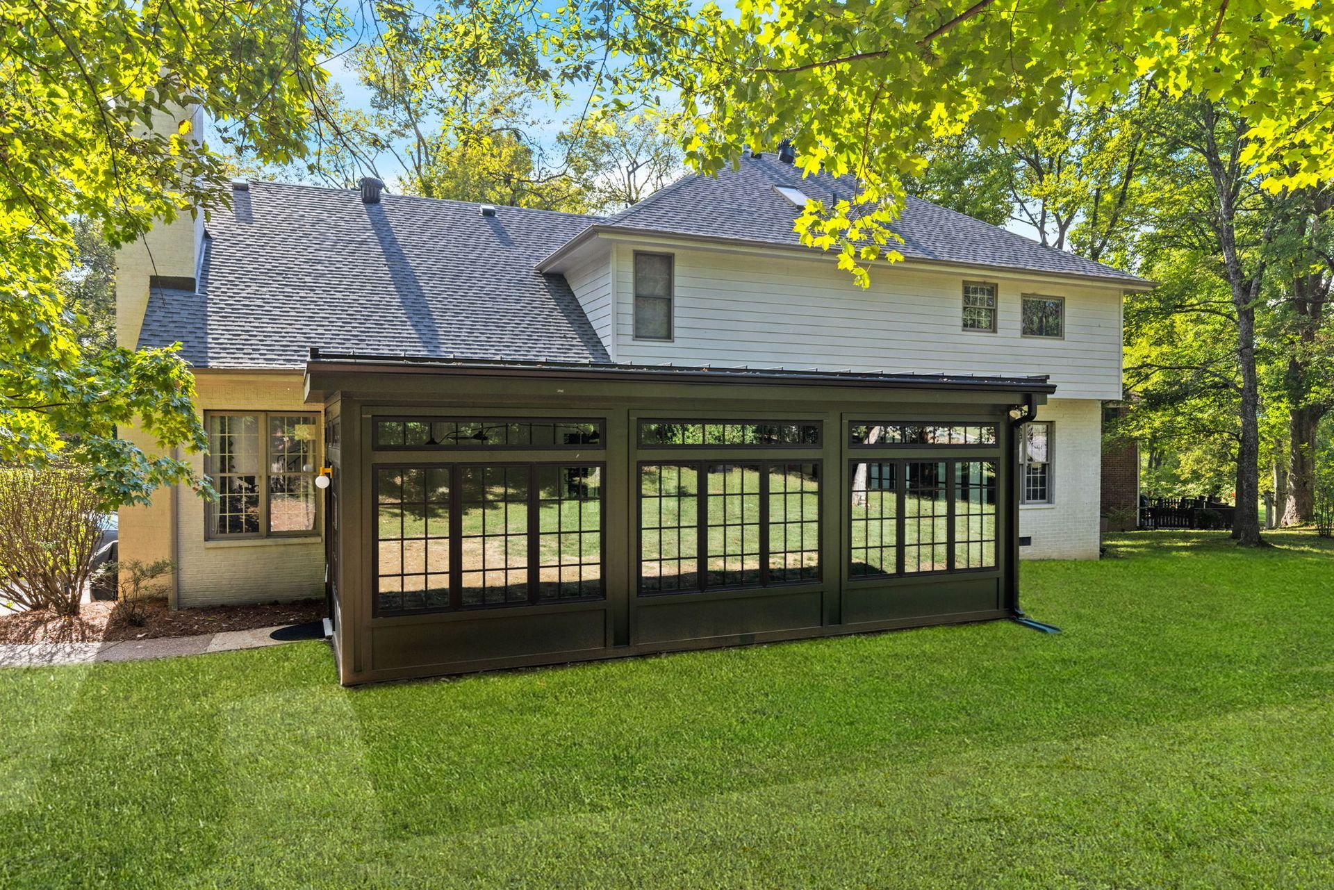 A house with a screened in porch in the backyard.