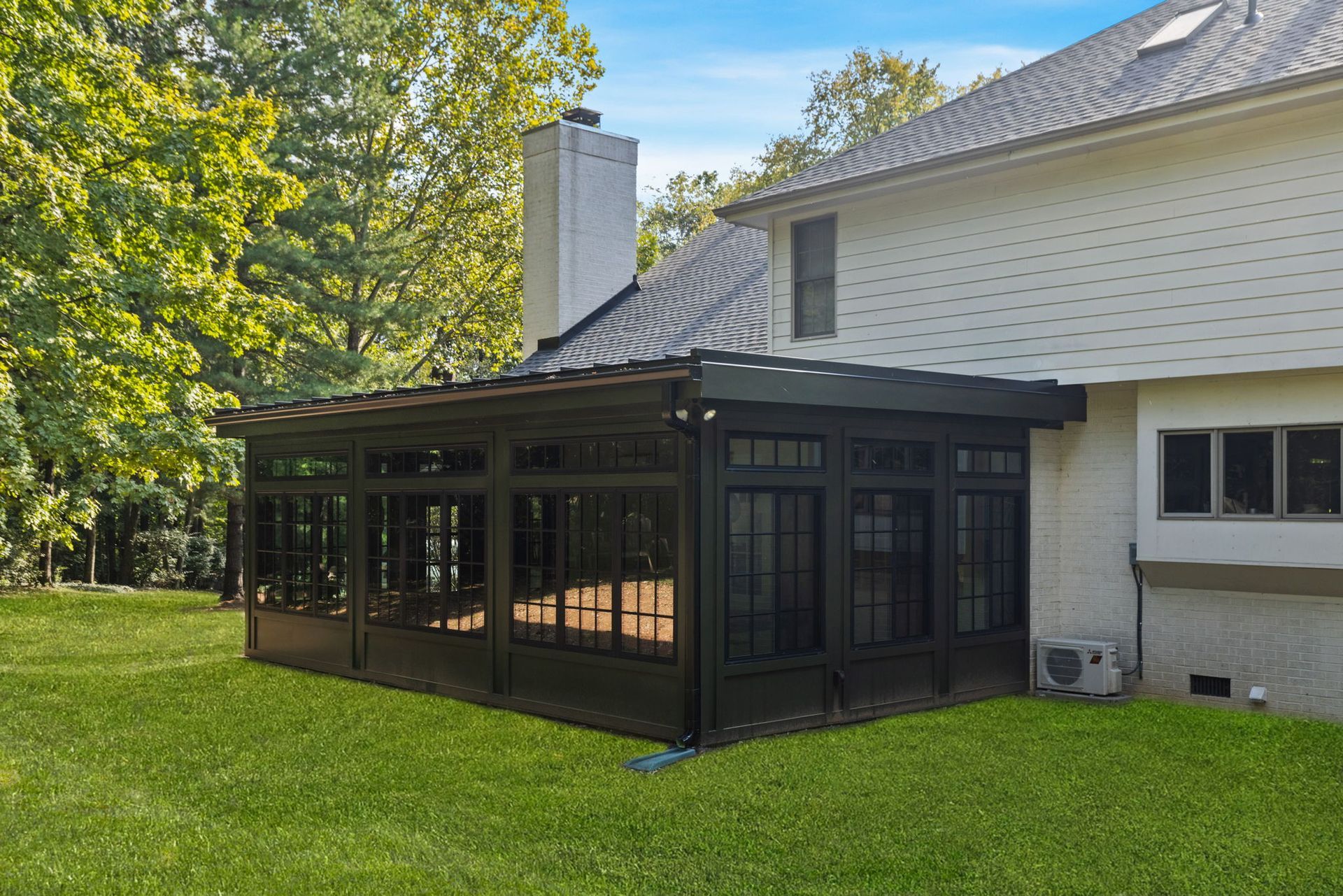 A house with a screened in porch in the backyard.