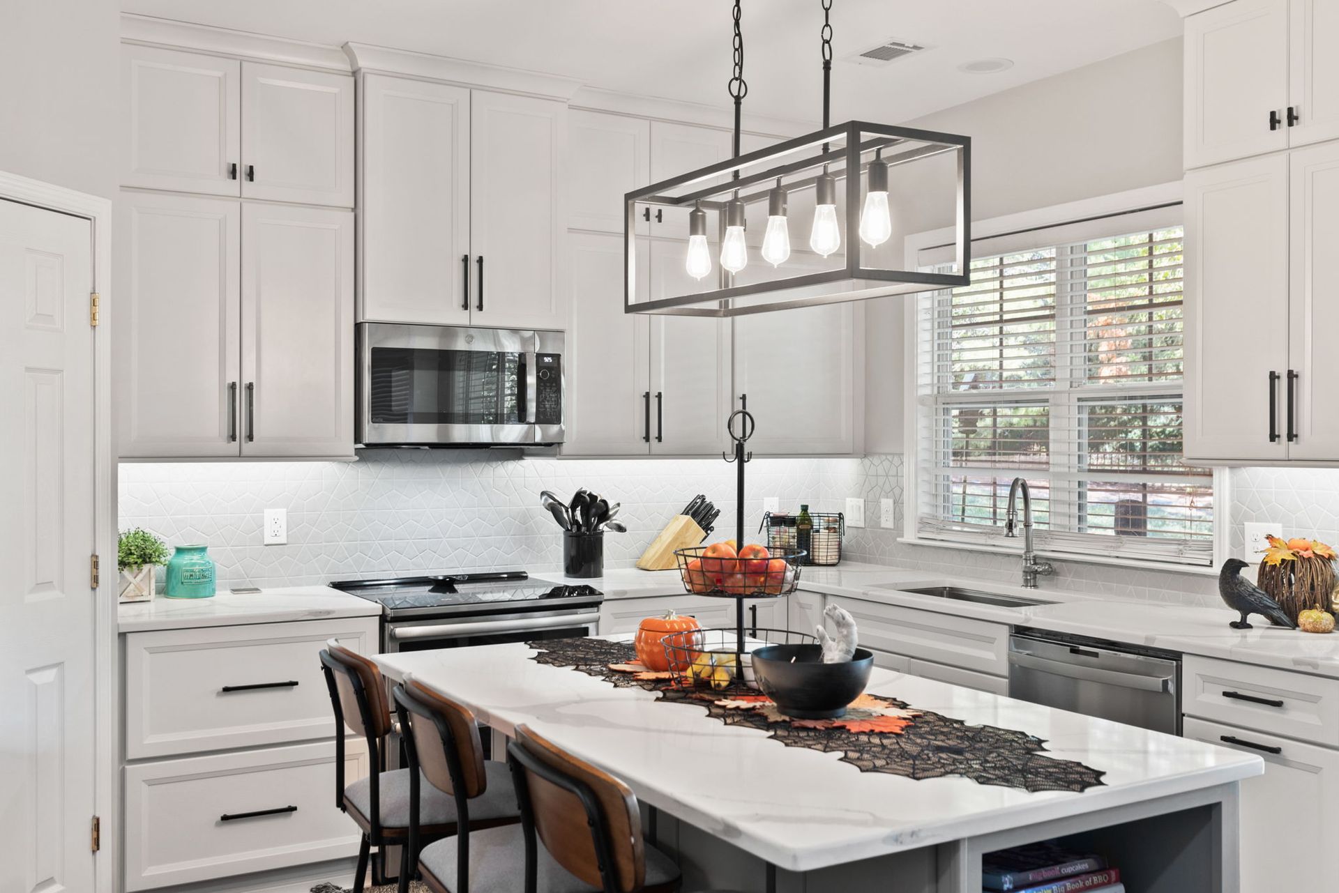 A kitchen with white cabinets , stainless steel appliances , and a large island.