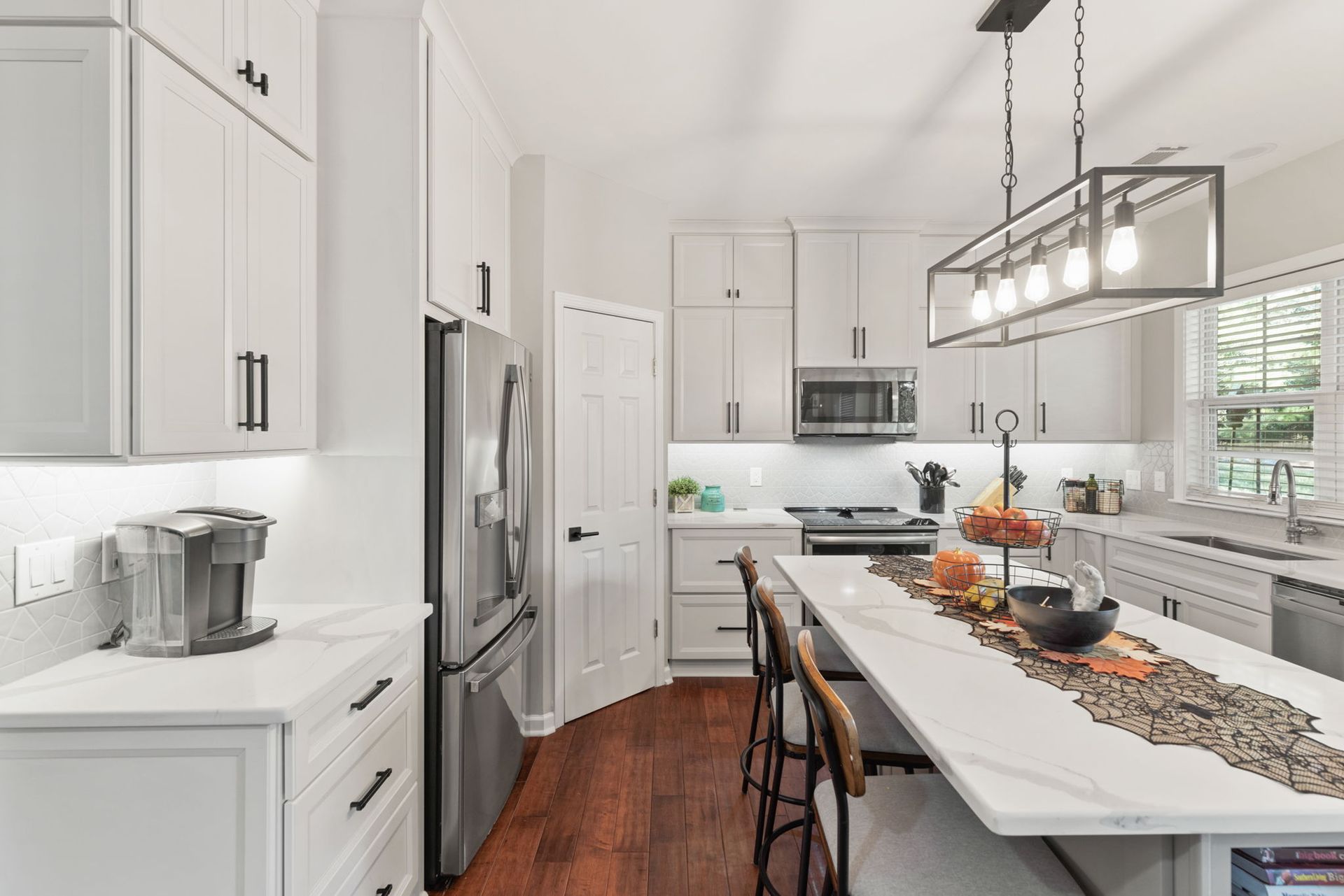 A kitchen with white cabinets , stainless steel appliances , and a large island.