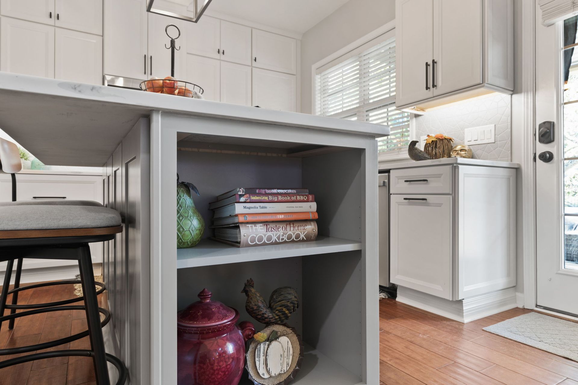 A kitchen with a shelf filled with books and a stack of books on it.