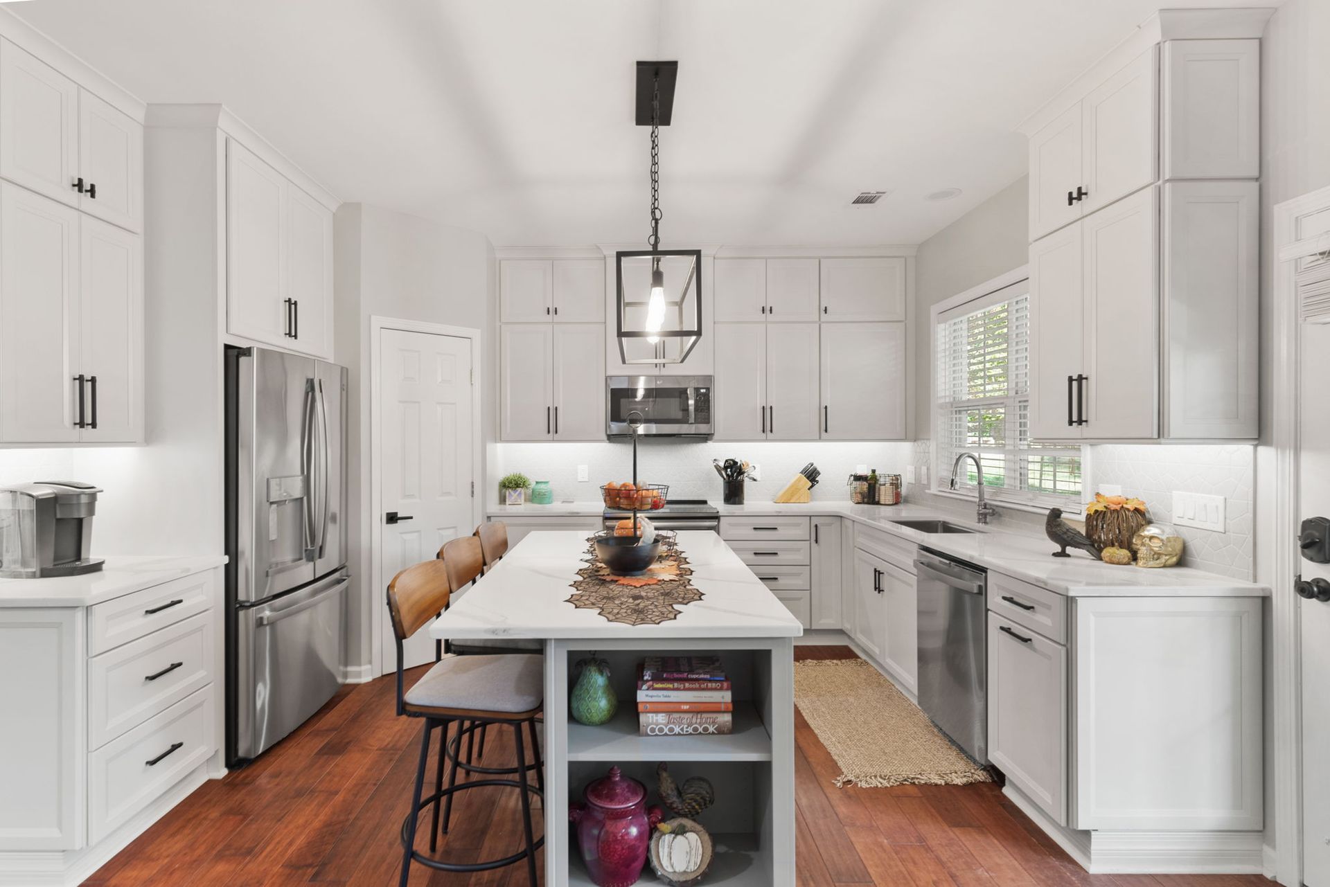 A kitchen with white cabinets and stainless steel appliances and a large island in the middle.