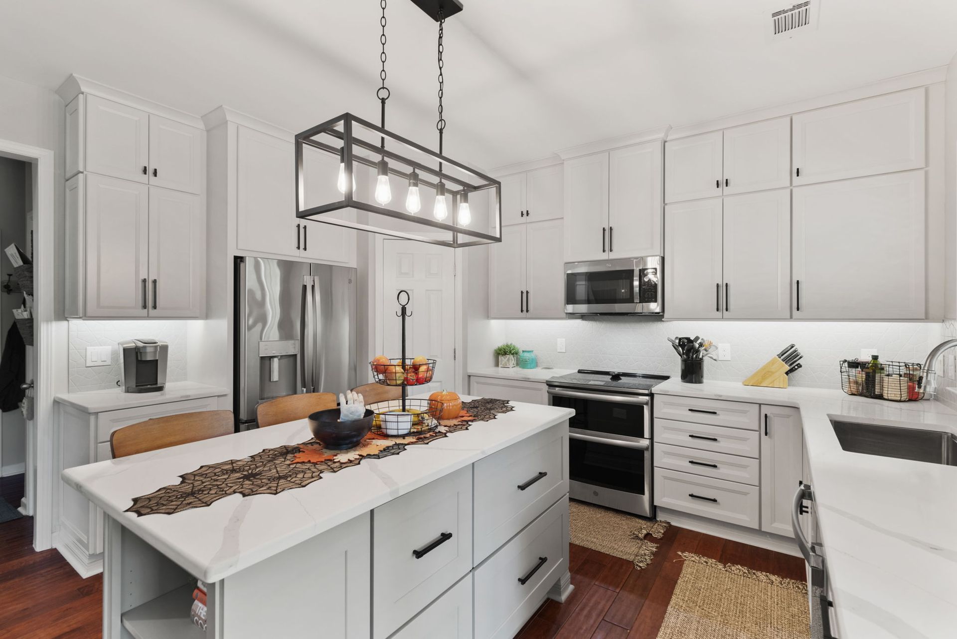 A kitchen with white cabinets , stainless steel appliances , and a large island.