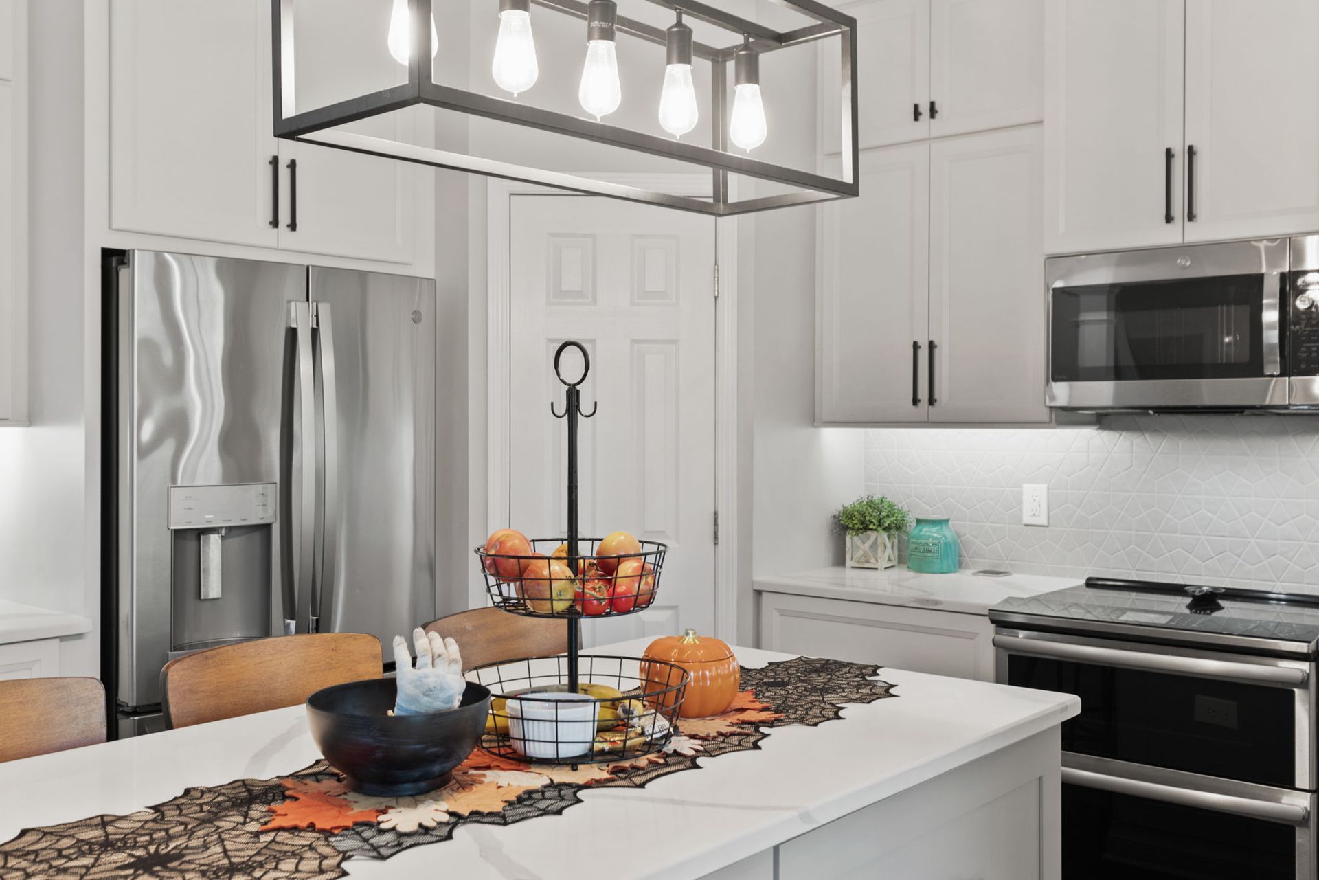 A kitchen with white cabinets , stainless steel appliances , and a large island