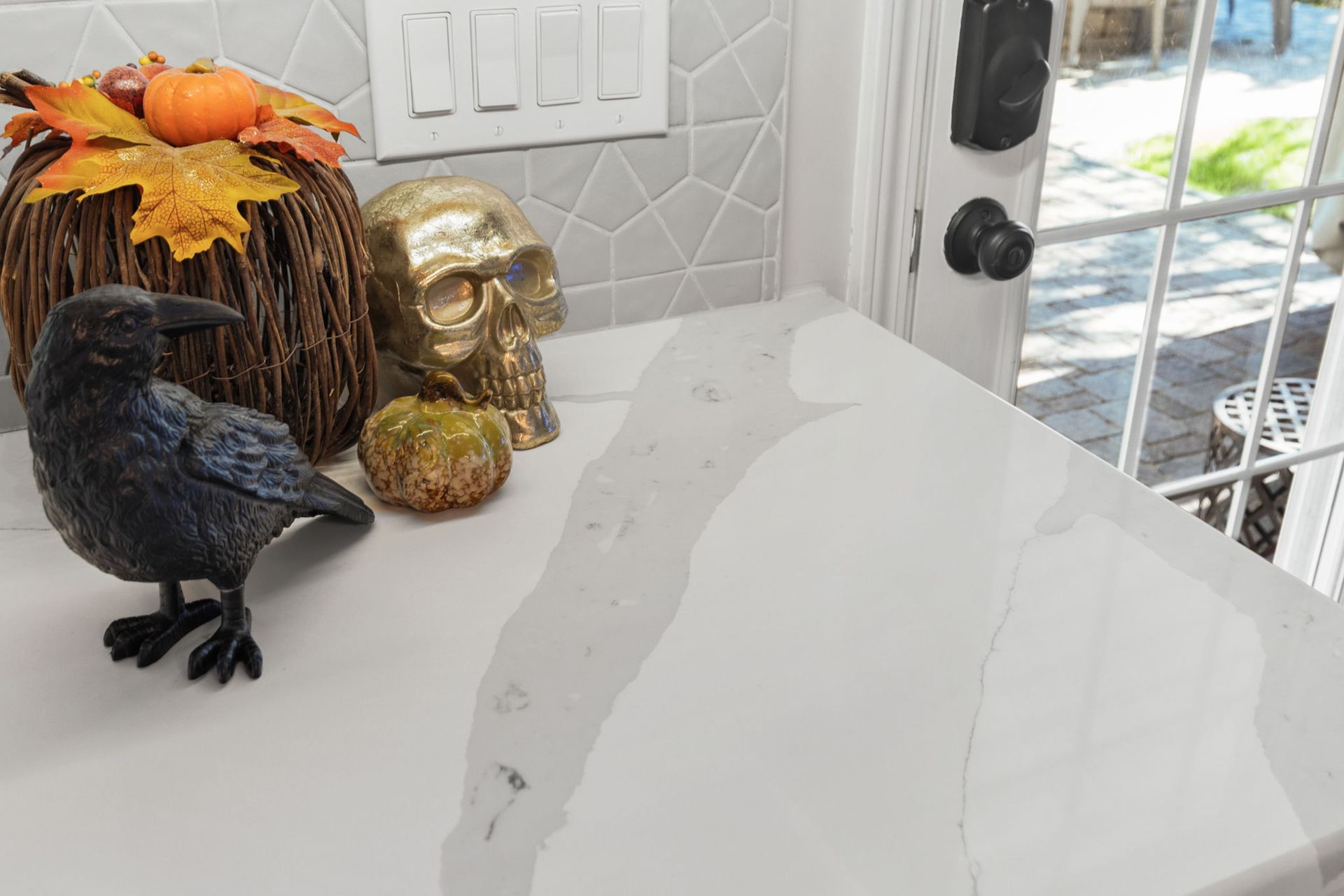A statue of a bird is sitting on a counter next to a pumpkin and a skull.