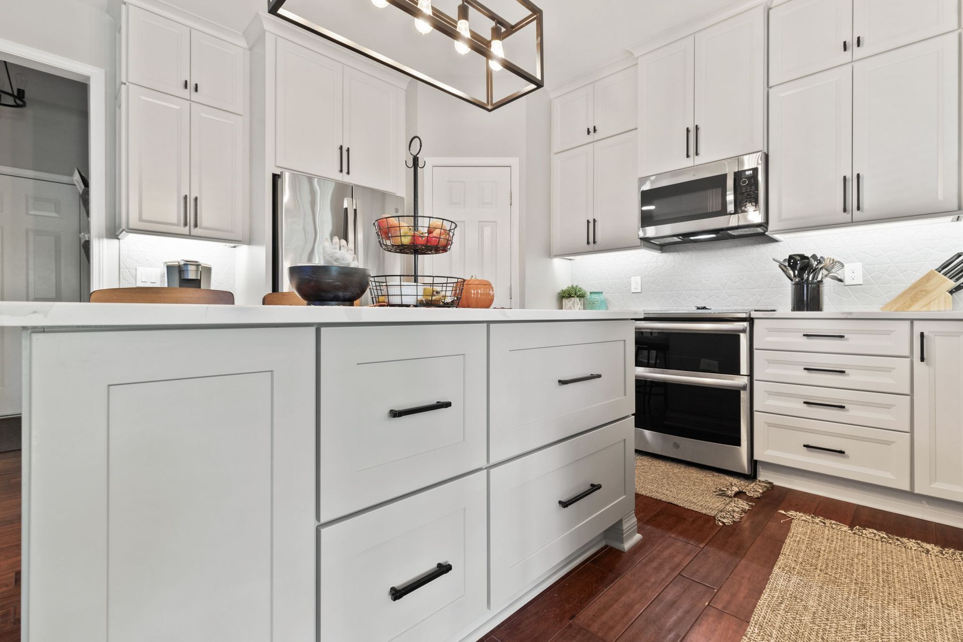 A kitchen with white cabinets , stainless steel appliances , and a large island.