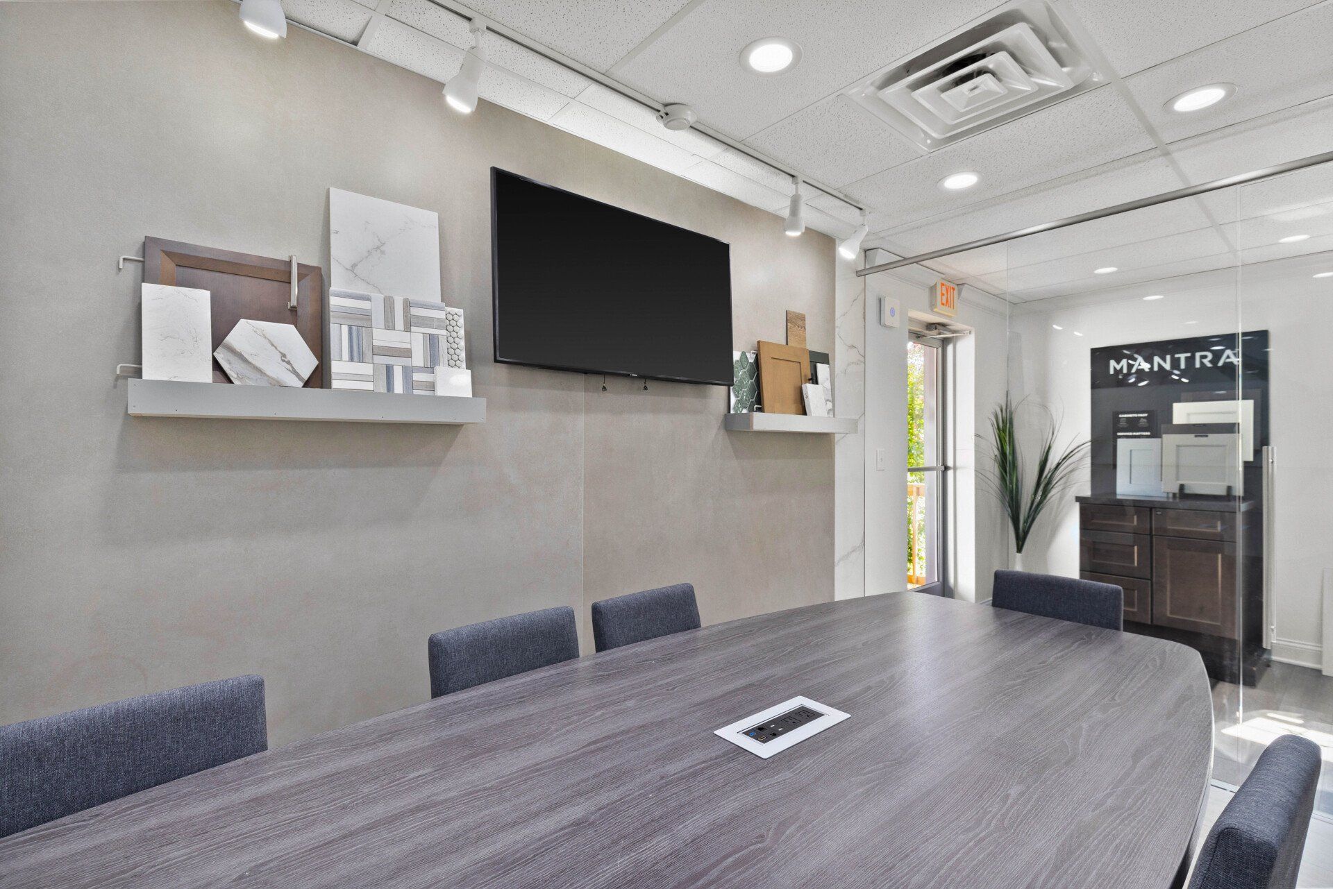 A conference room with a long table and chairs and a flat screen tv on the wall.