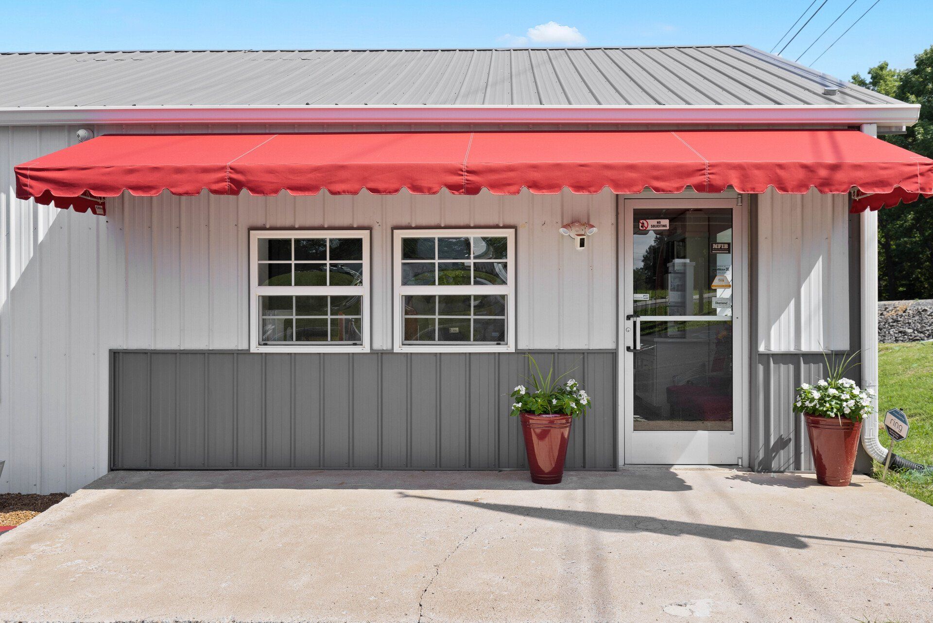 A white building with a red awning over the door