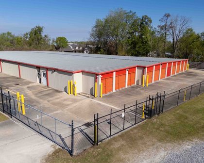 Aerial view of drive-up storage units with orange doors and perimeter fencing at Premier Storage & Shipping, Addis, LA