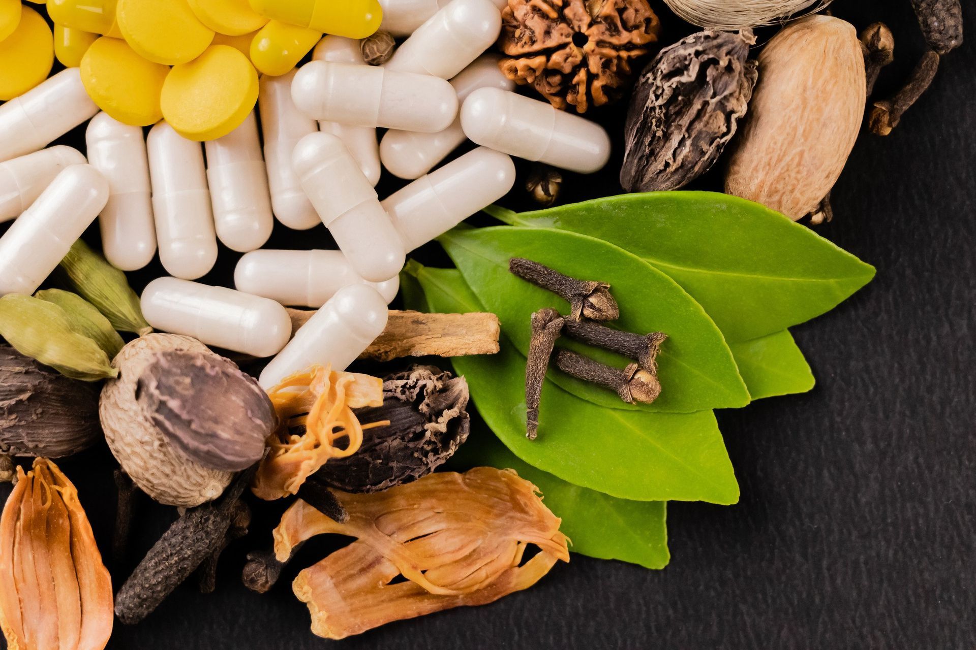 A pile of pills , leaves , and spices on a table.