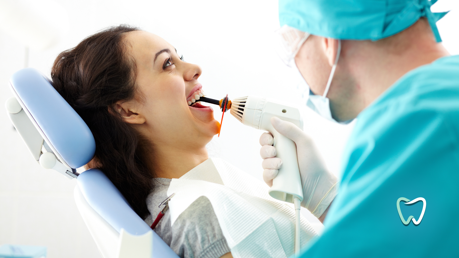A woman is sitting in a dental chair getting her teeth examined by a dentist.