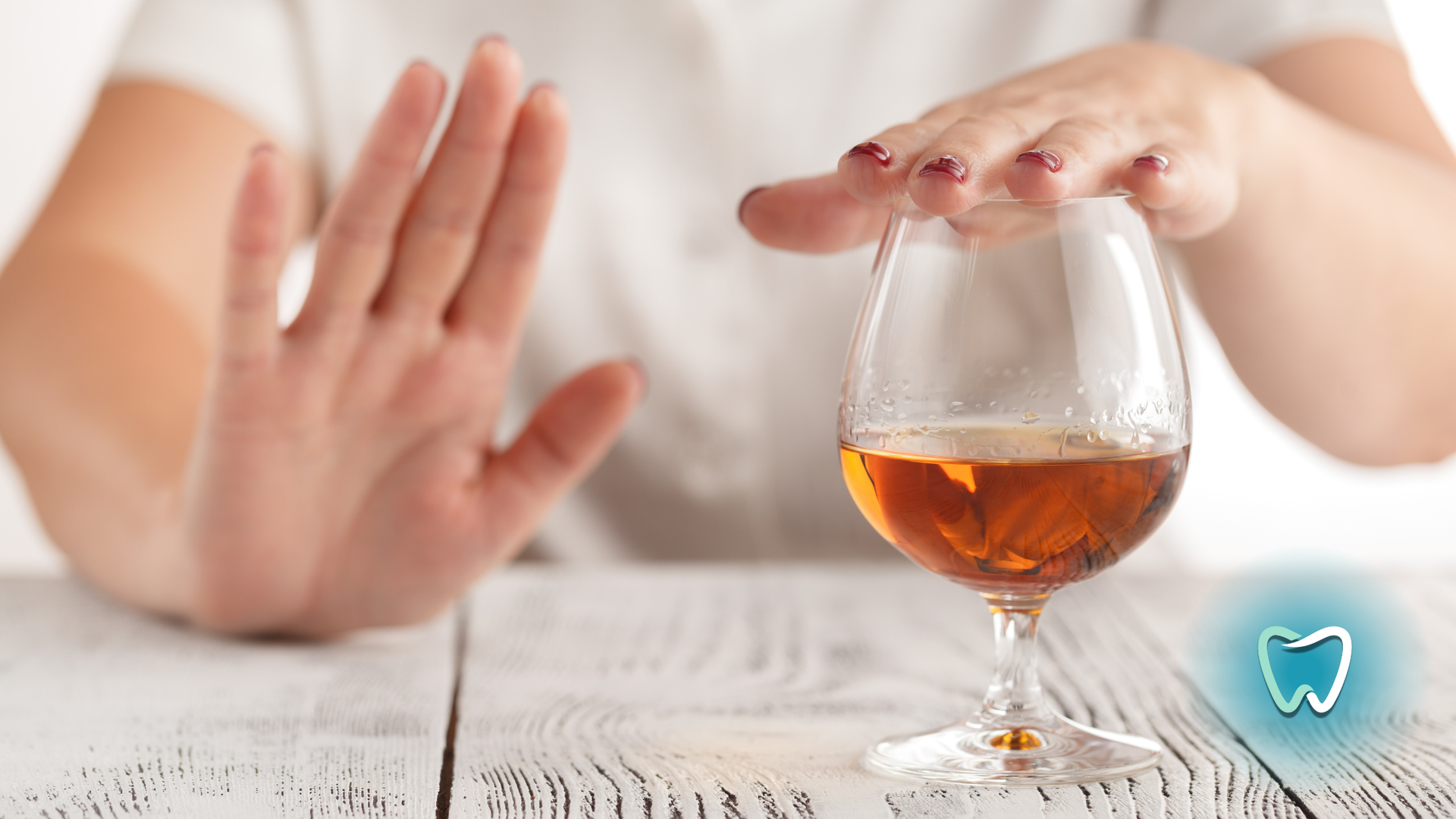 A woman is refusing to drink a glass of wine.