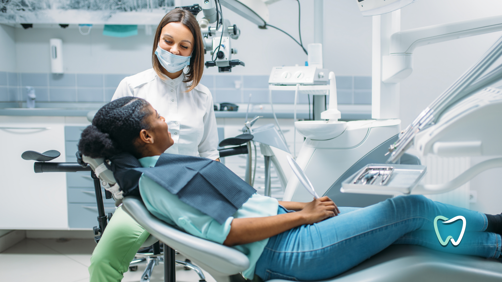 A woman is laying in a dental chair talking to a dentist.