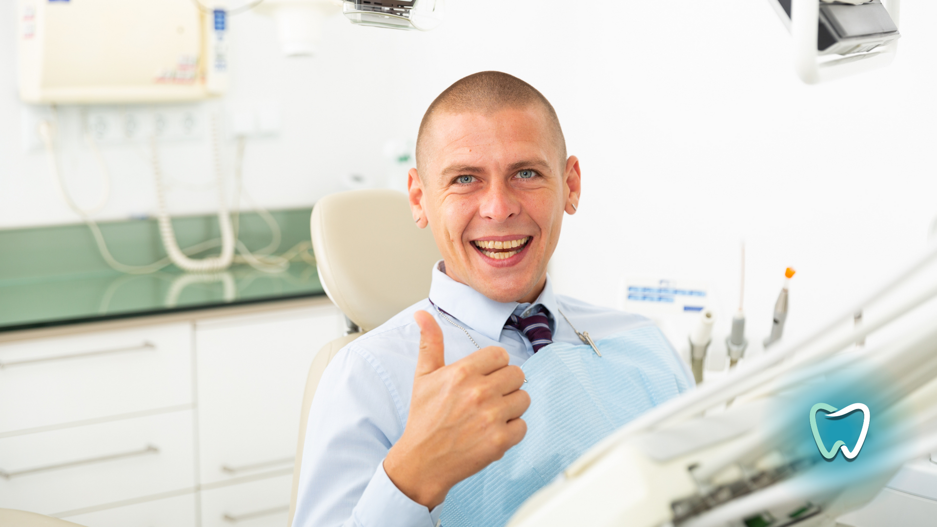 A man is sitting in a dental chair and giving a thumbs up.