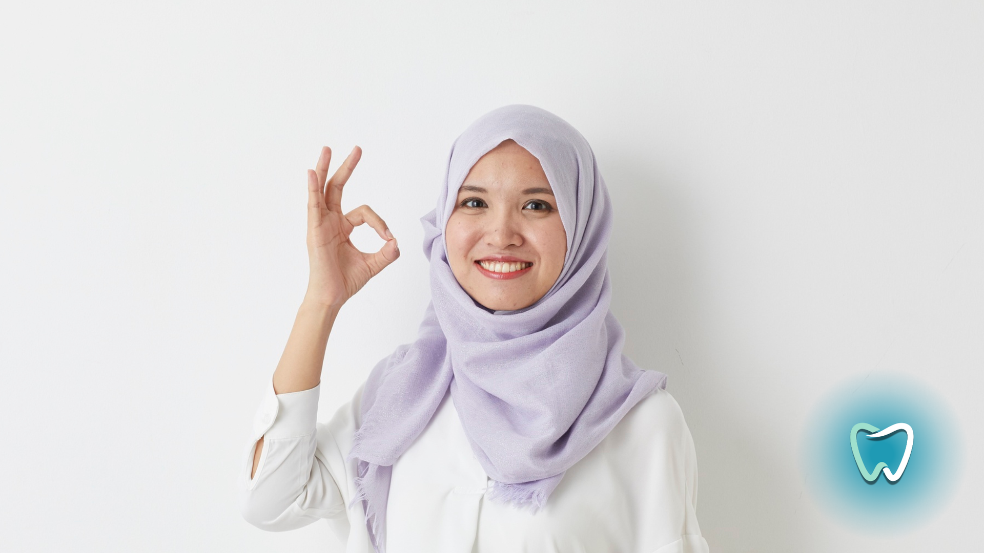Woman in lavender hijab smiling, making an