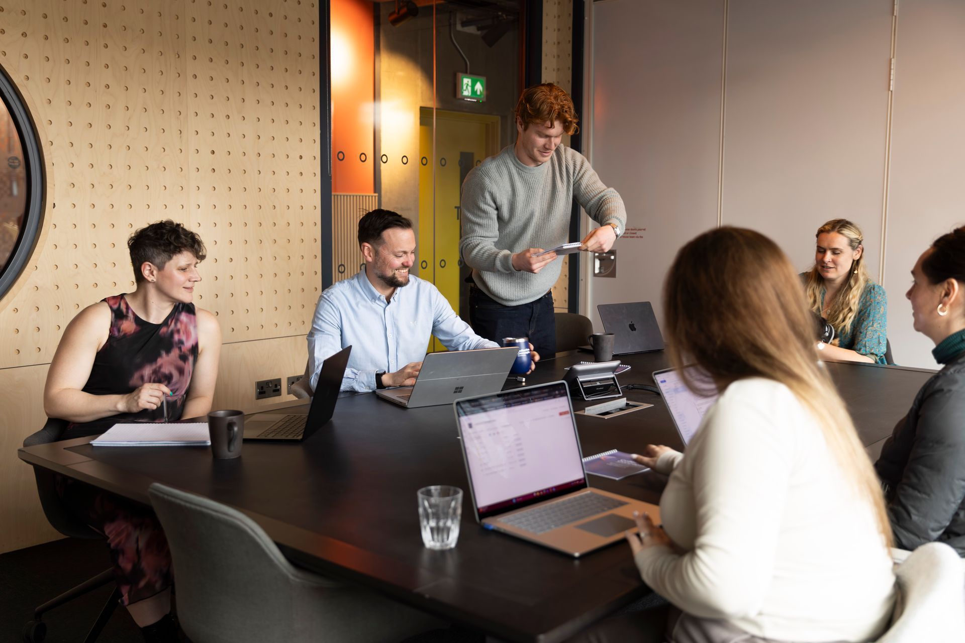 Team meeting around a conference table with laptops in a modern office.