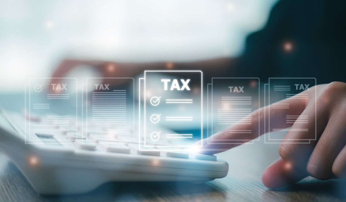 Hand tapping a tablet with floating TAX icons, suggesting online tax filing