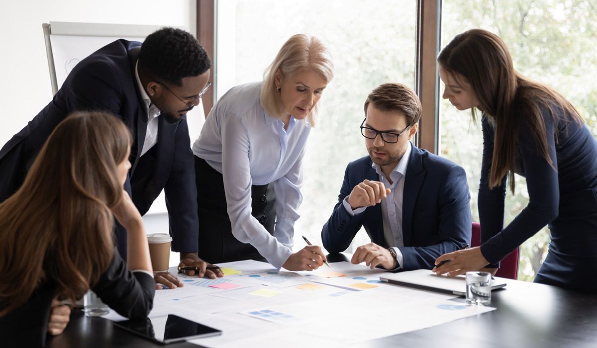 Colleagues gathered around a conference table reviewing documents in a bright office