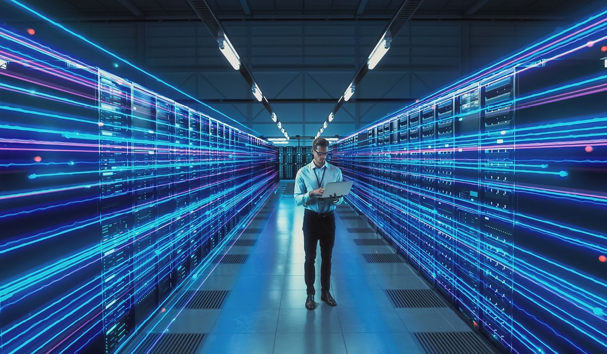 Person standing in a neon-lit data corridor with blue light trails and server racks on both sides