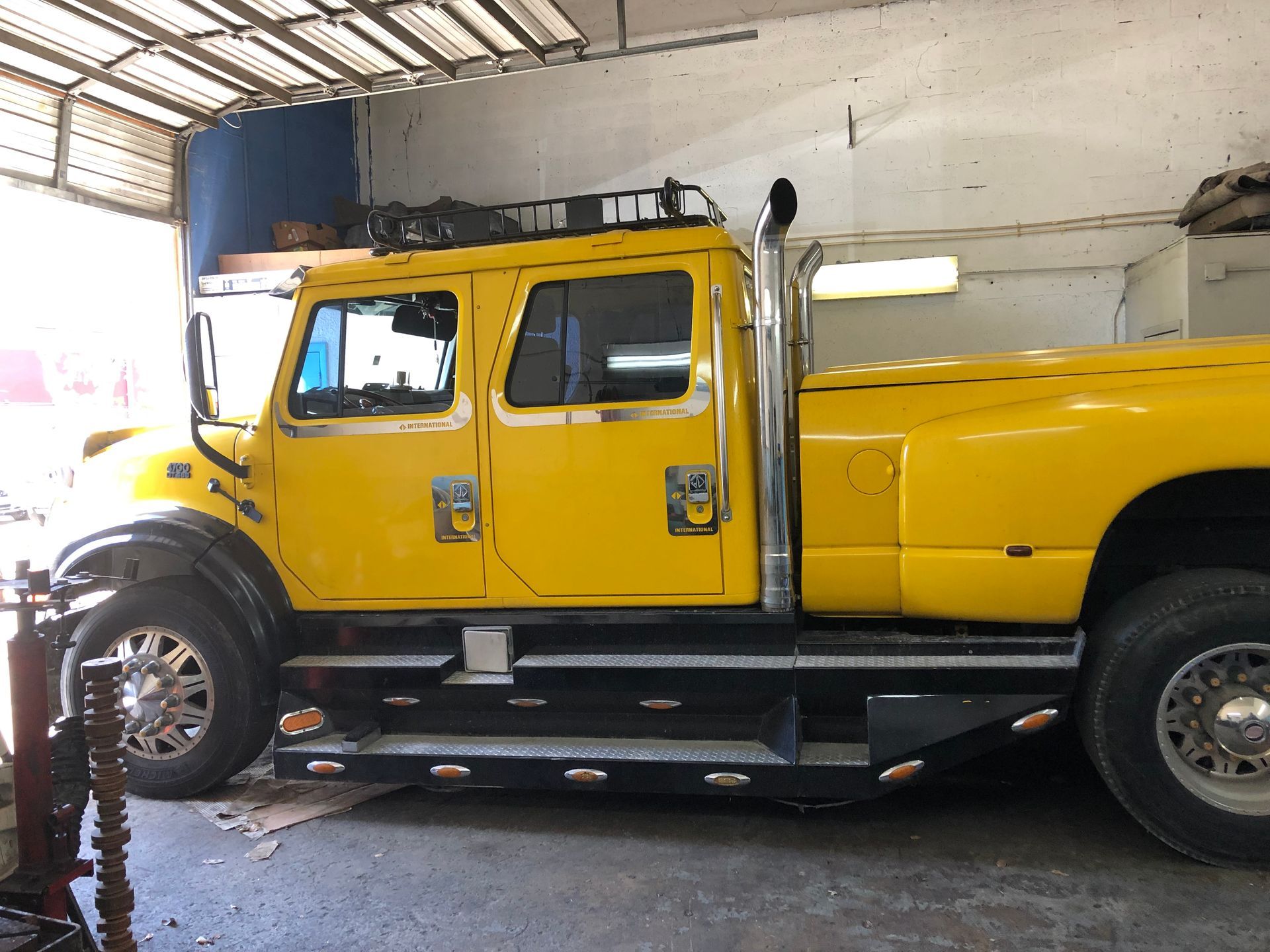 A yellow truck with the letter e on the side is parked in a garage.