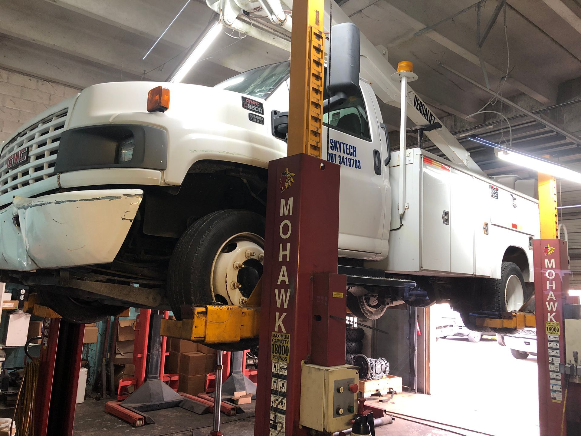 A white truck is sitting on a lift in a garage.