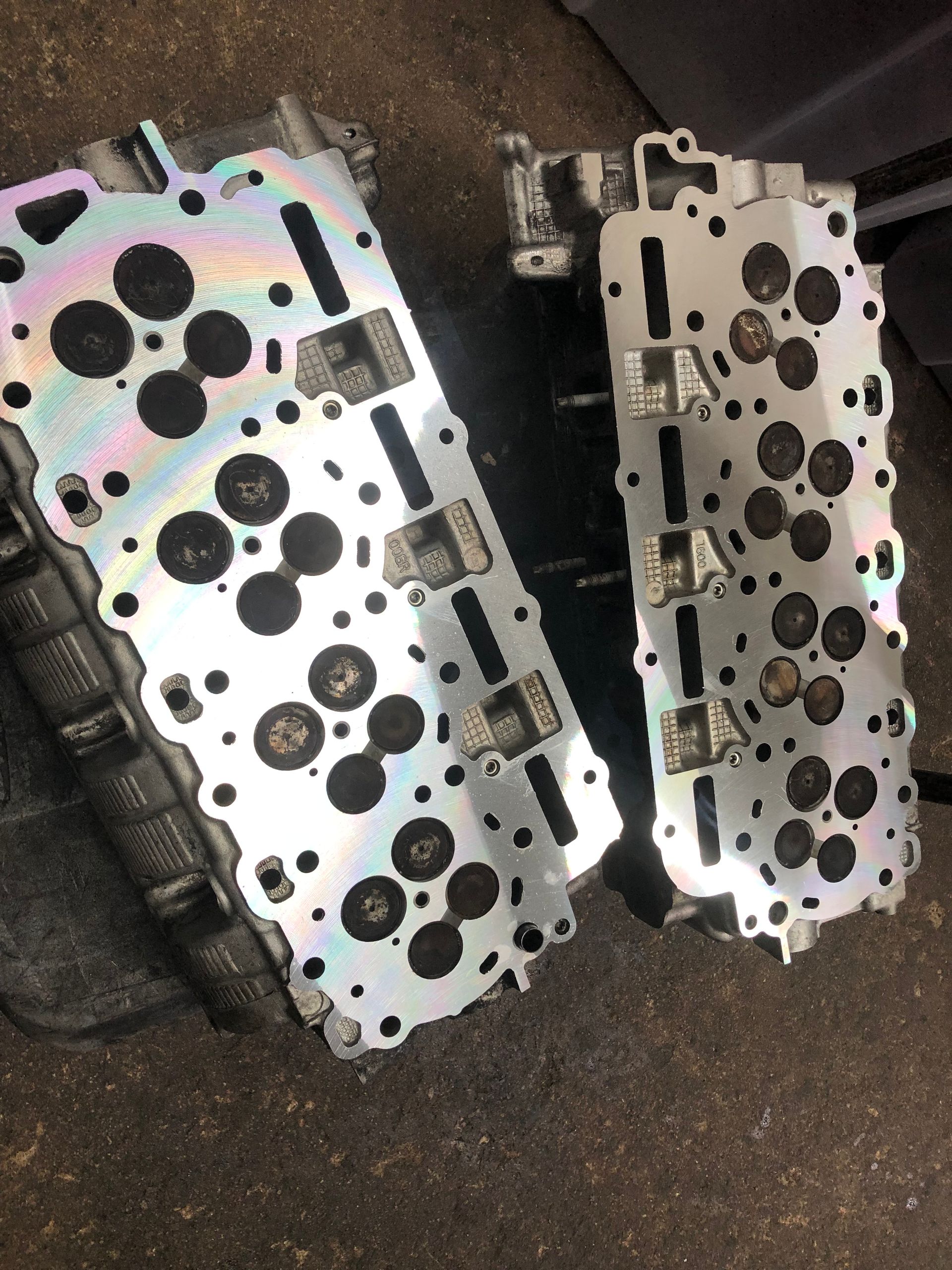 Two cylinder heads are sitting next to each other on the ground.
