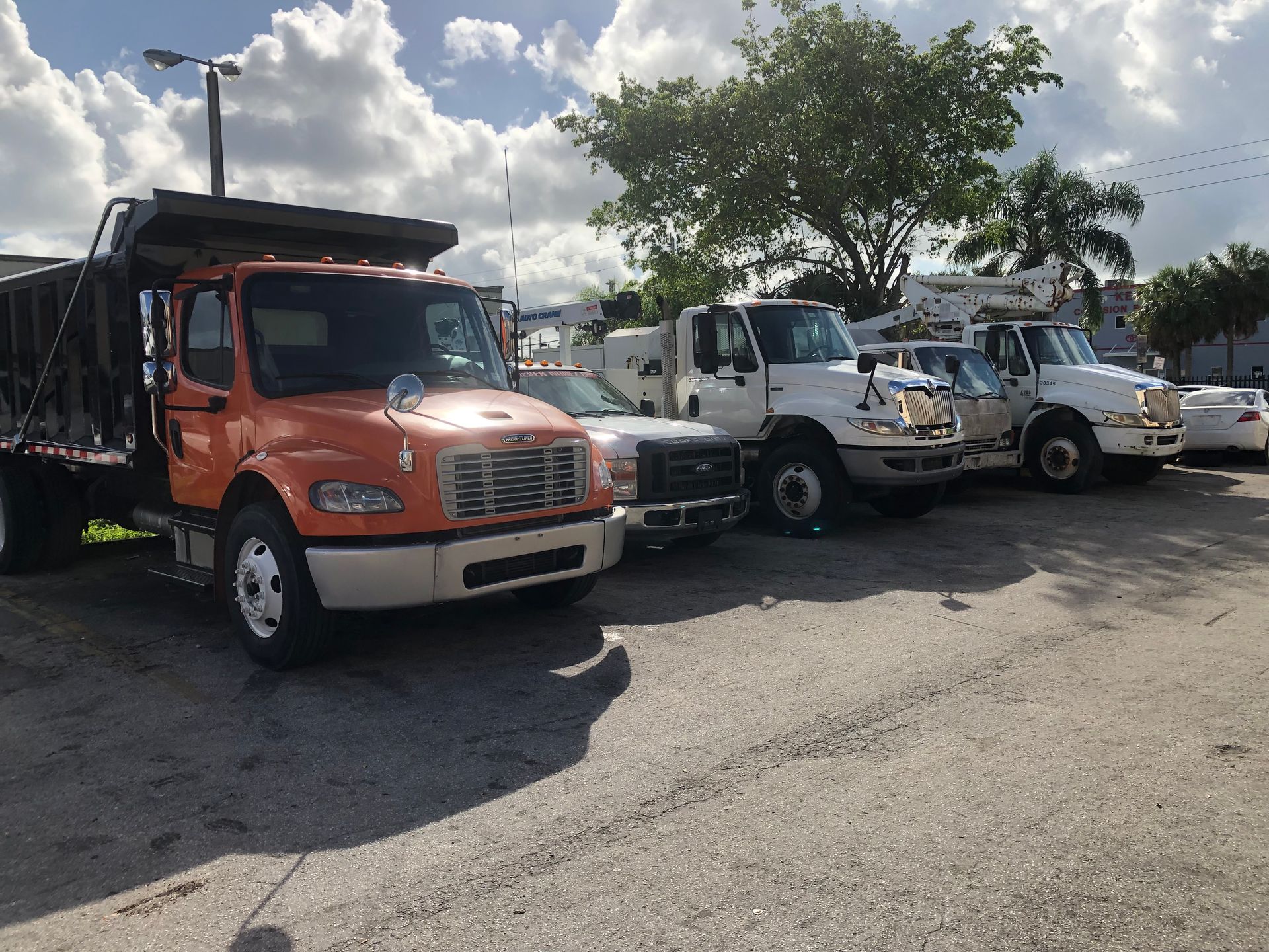 A row of trucks are parked in a parking lot.