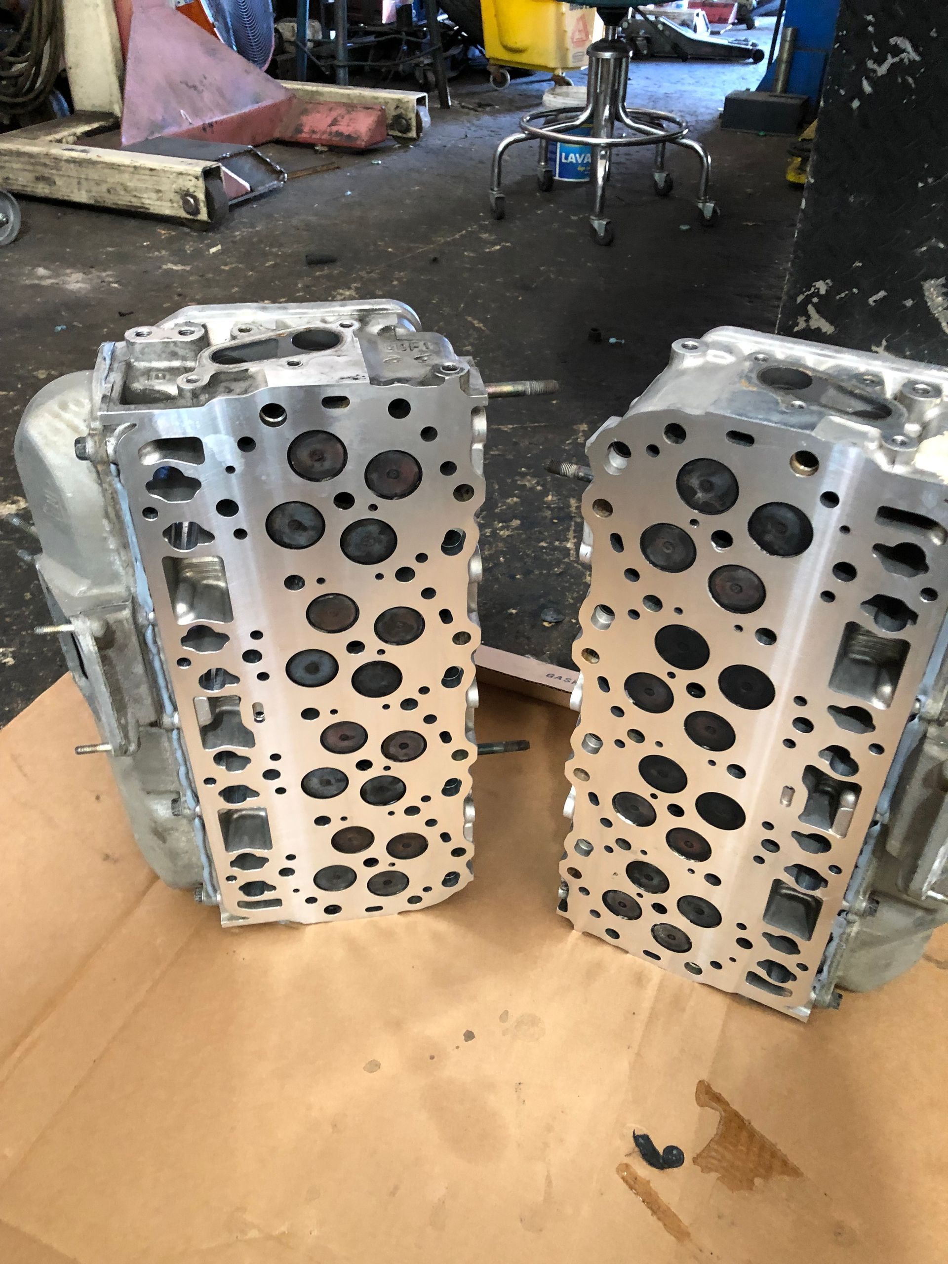 Two engine heads are sitting on top of a piece of cardboard.