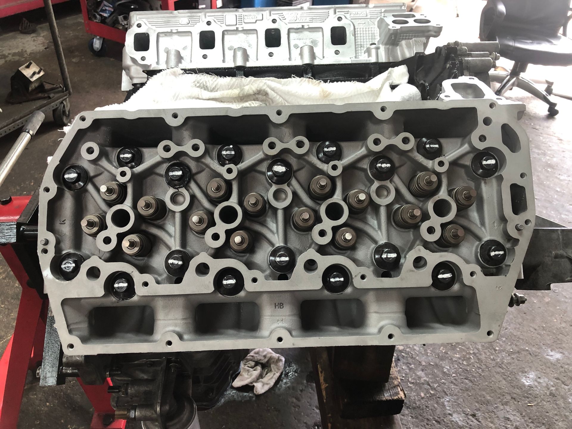 A cylinder head is sitting on a table in a garage.