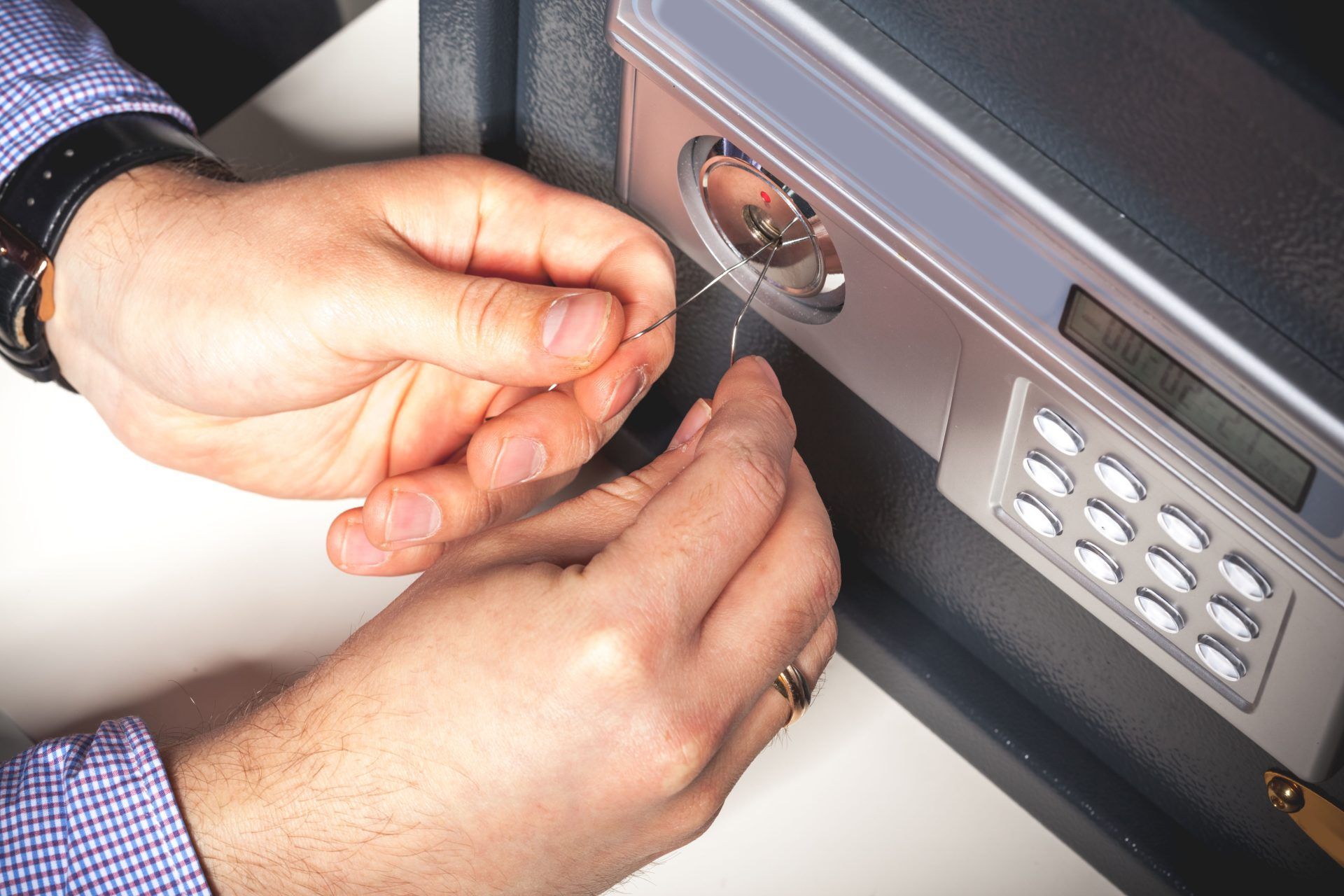 A man is opening a safe with a screwdriver.