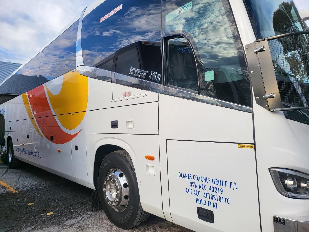 A White and Yellow Bus is Parked on the Side of the Road — Signworld In Mitchell, ACT