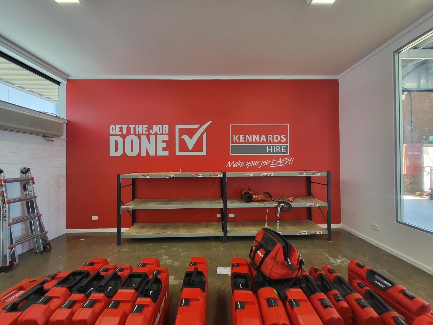 A room with a red wall that says get the job done — Signworld In Mitchell, ACT