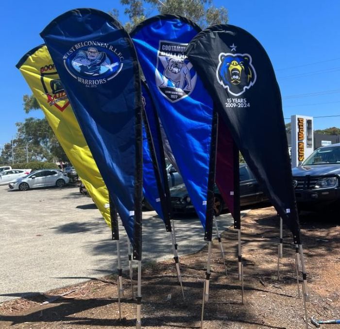 A Bunch of Flags Are Lined Up in a Parking Lot — Signworld In Mitchell, ACT