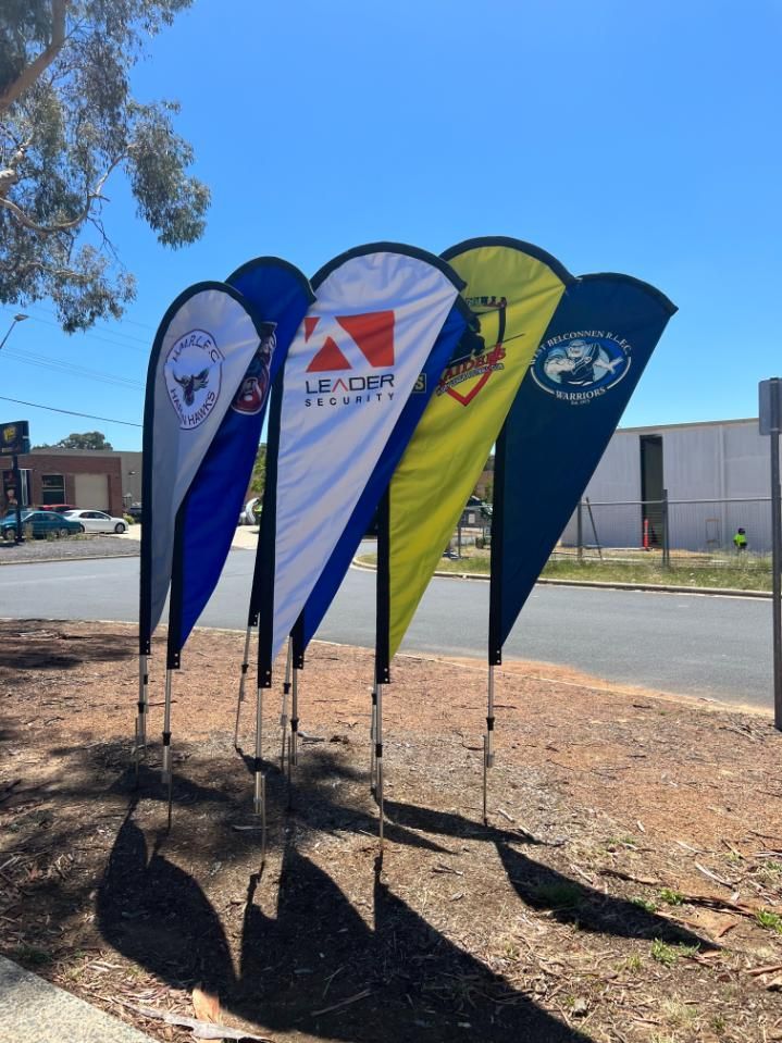A Bunch of Flags Are Lined Up on the Side of the Road — Signworld In Mitchell, ACT