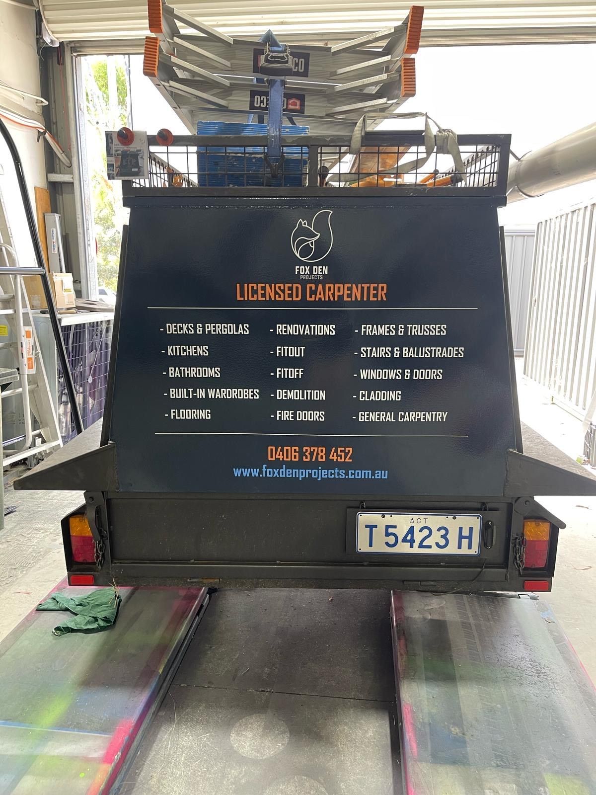 A black trailer with a sign on the back is parked in a garage — Signworld In Mitchell, ACT